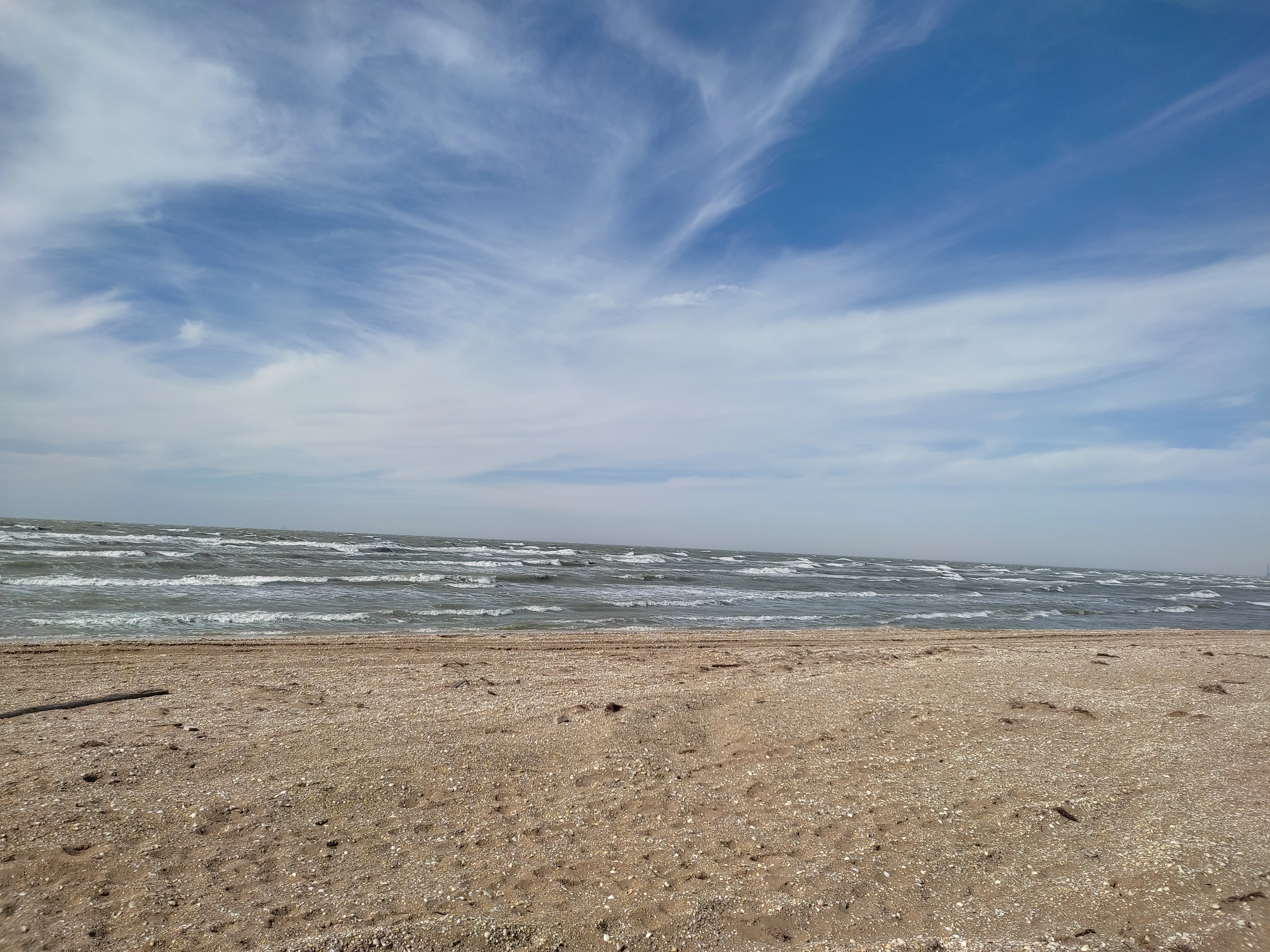 Sandy beach with gentle ocean waves and scattered clouds in the sky