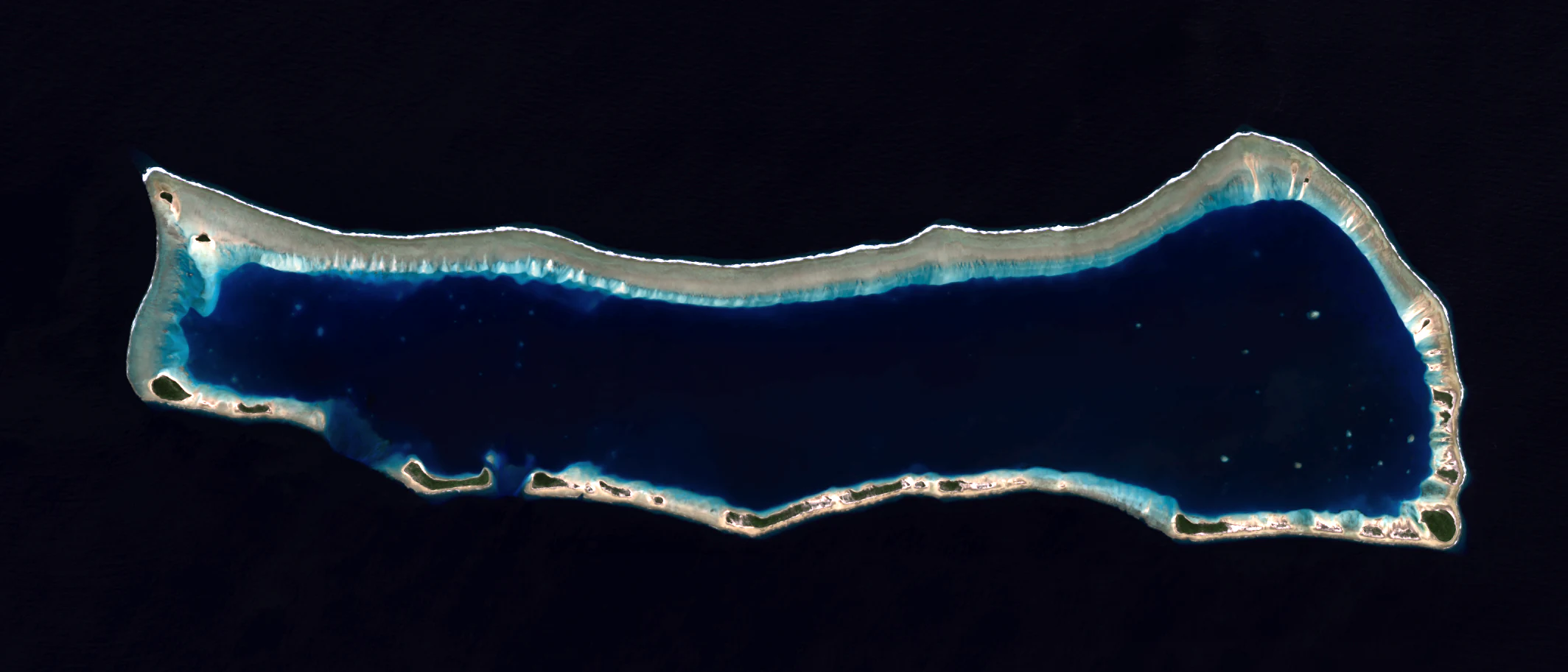 Top-down satellite view of Ailinginae Atoll, a coral ring structure surrounding a dark blue lagoon, set against a black background.