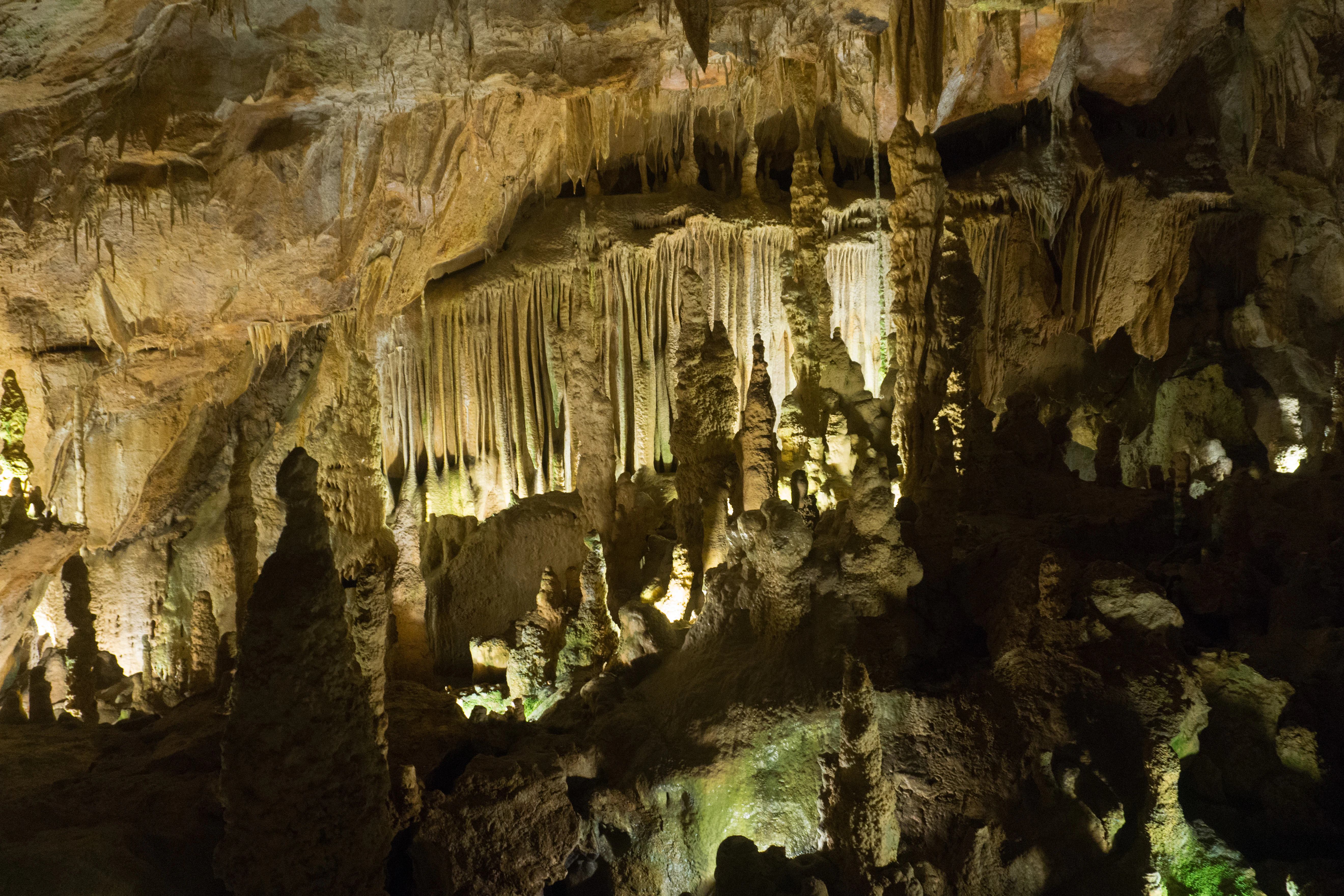 Cave interior featuring stalactites hanging from the ceiling and rock formations illuminated by artificial lighting