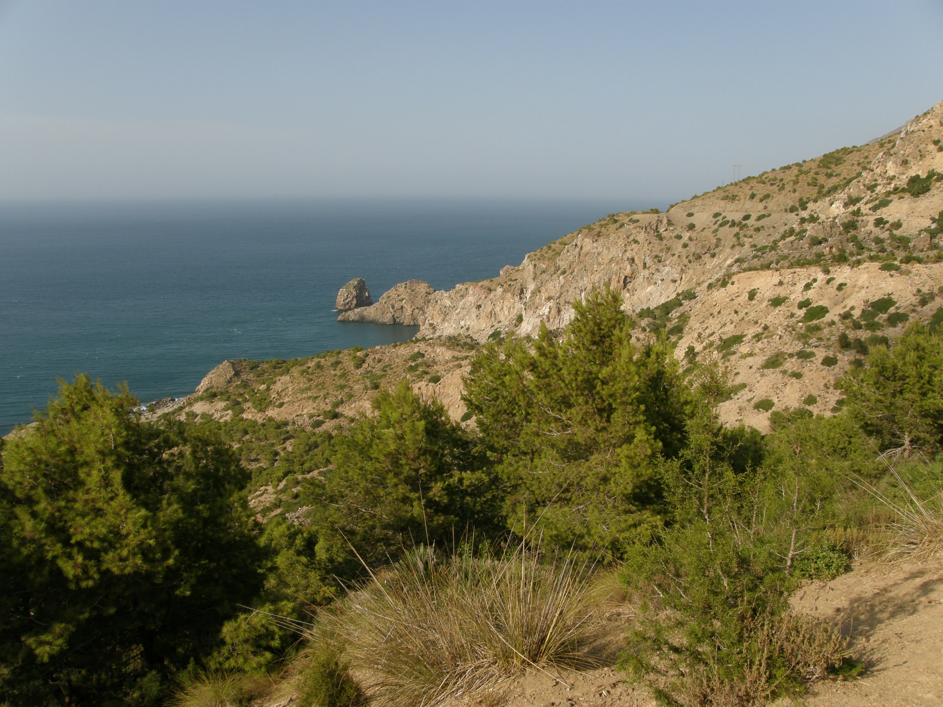 Rocky mountain coastline with blue sea, Mediterranean vegetation, and clear sky