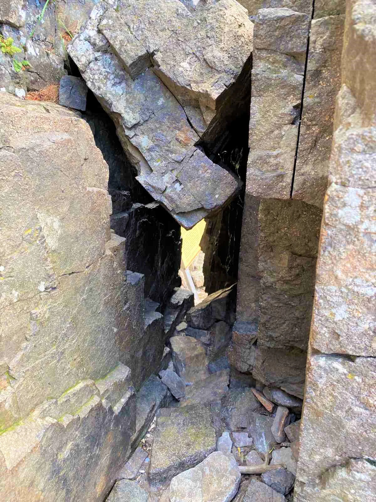 Narrow passage formed by large rocks with a light source visible at the far end