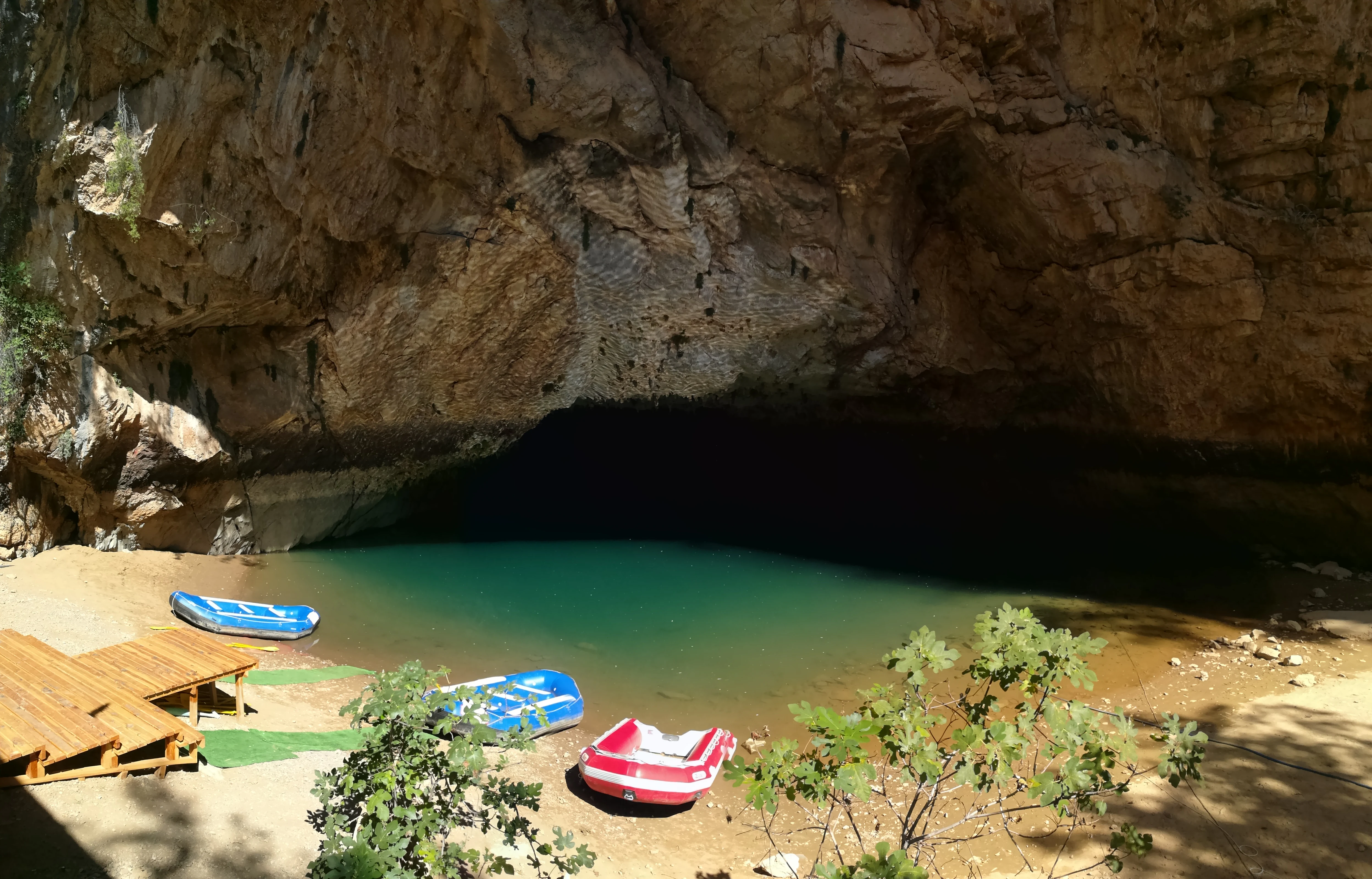 Boats docked near cave entrance with turquoise underground lake