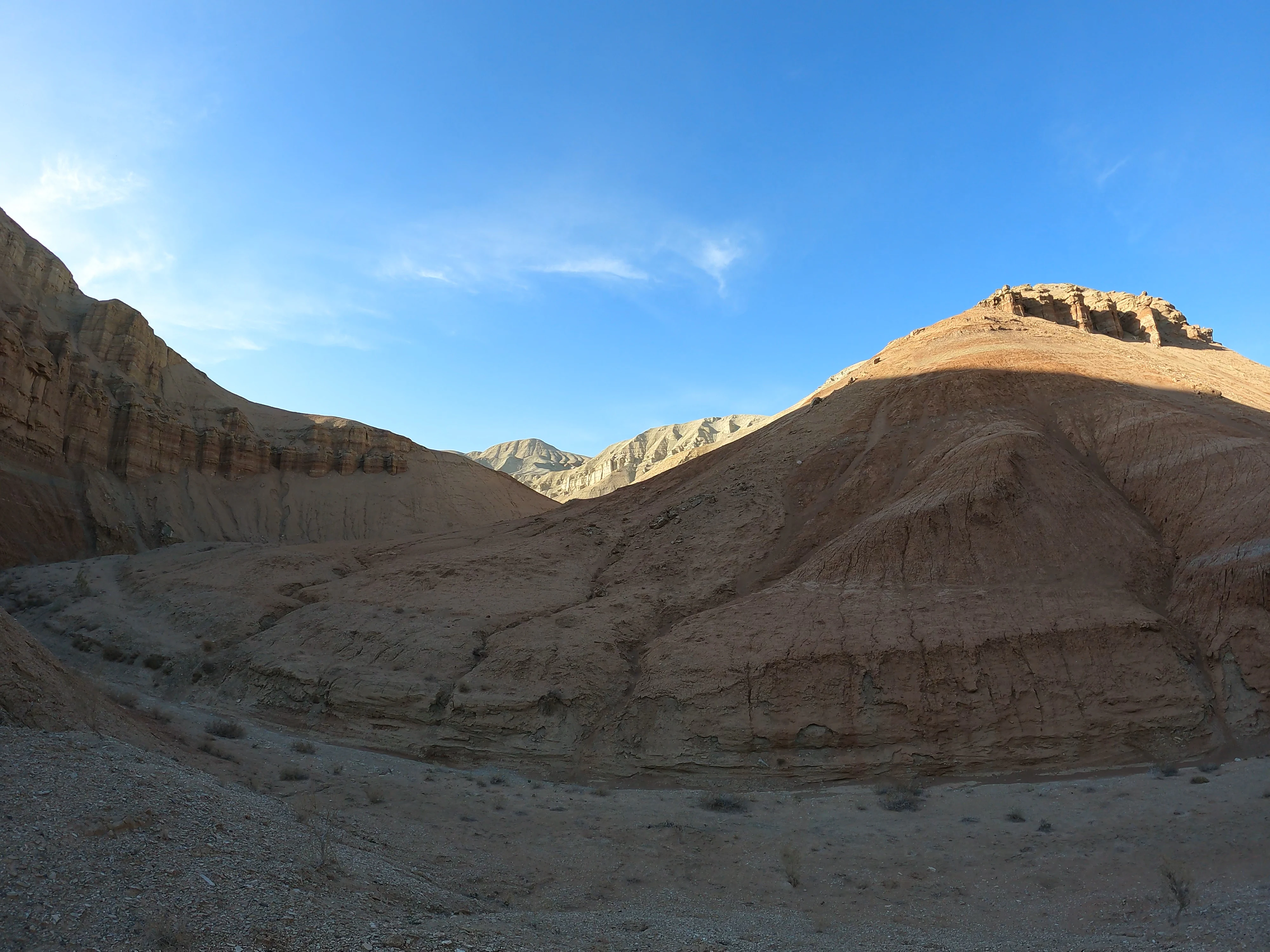 A wide desert landscape with rocky hills under a clear blue sky