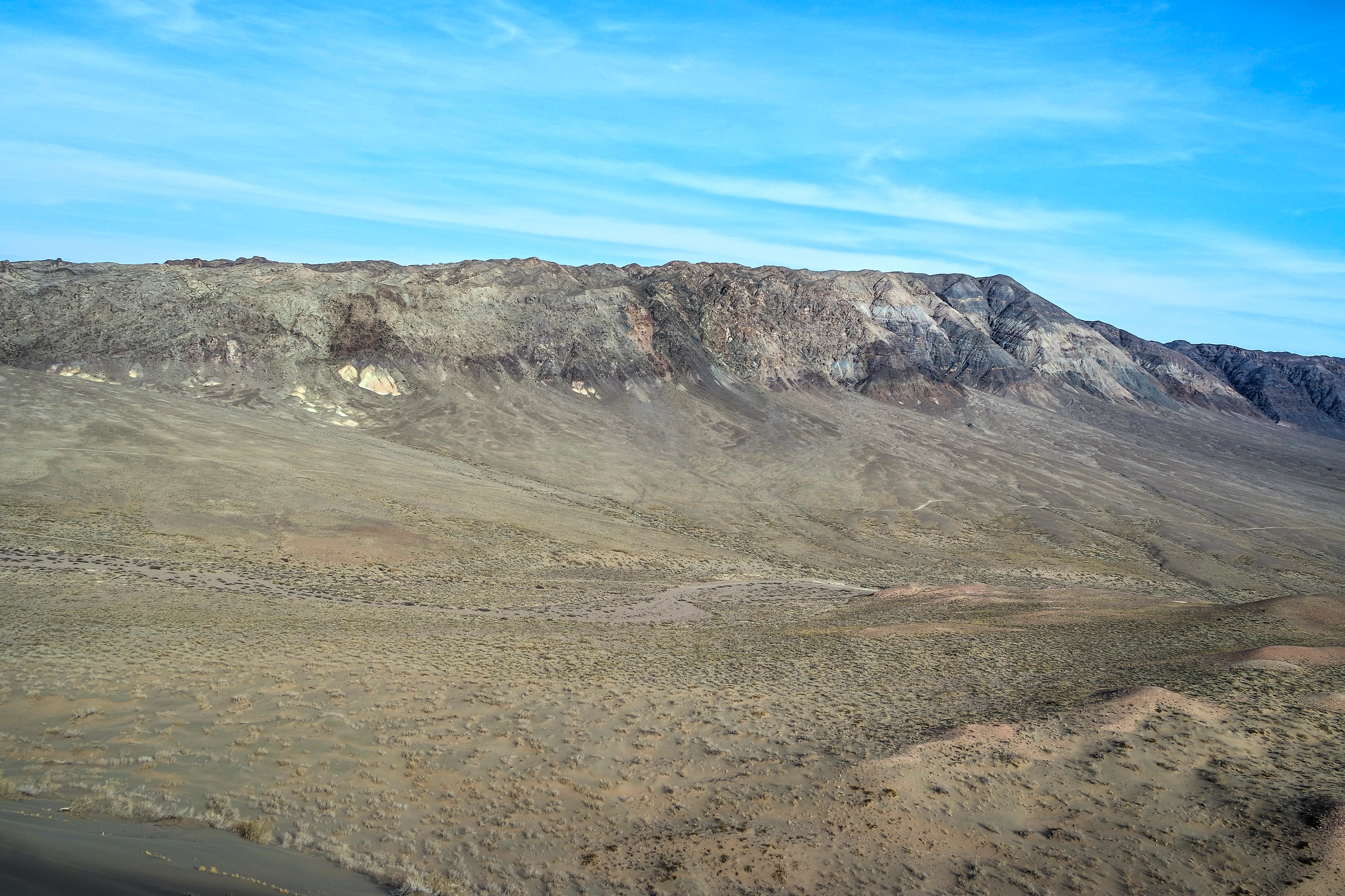 Wide desert landscape with rocky mountains under a blue sky with scattered clouds
