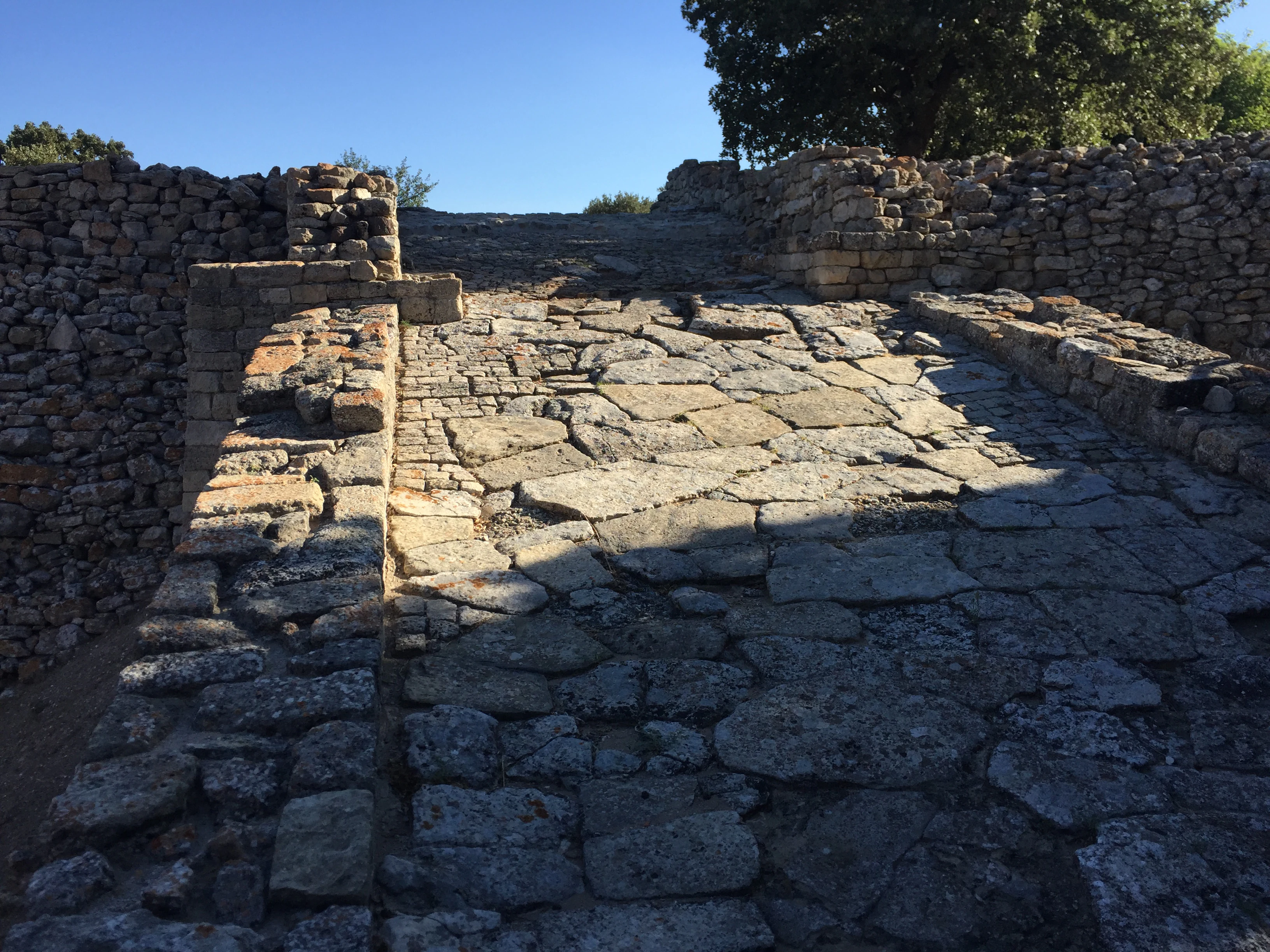 Stone pathway with ancient rampart walls on both sides under clear blue sky