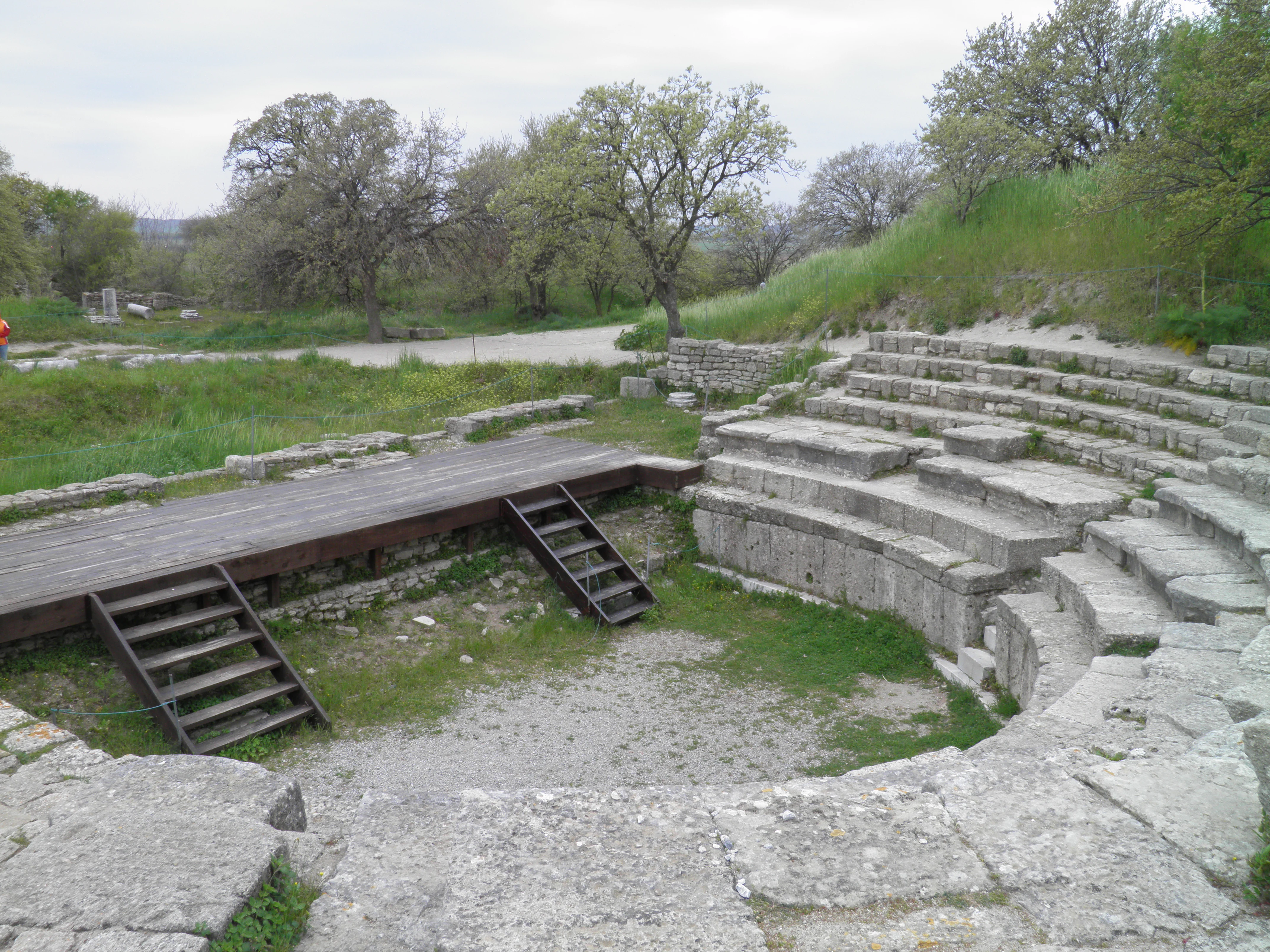 Stone steps and wooden platform of the Hadrianic Odeon with surrounding greenery and trees