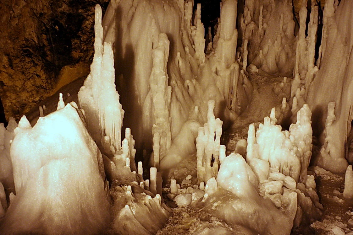 Interior view of a cave with prominent ice stalactites and stalagmites in a cavernous space
