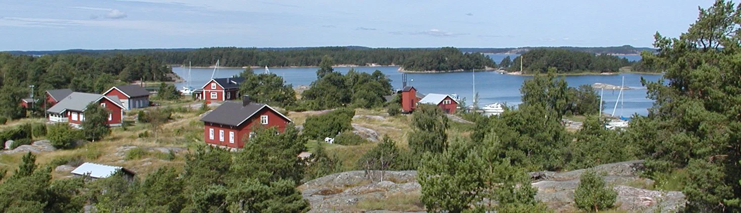 Panoramic view of Gullkrona featuring red houses, rocky terrain, trees, and multiple islands in the Archipelago Sea