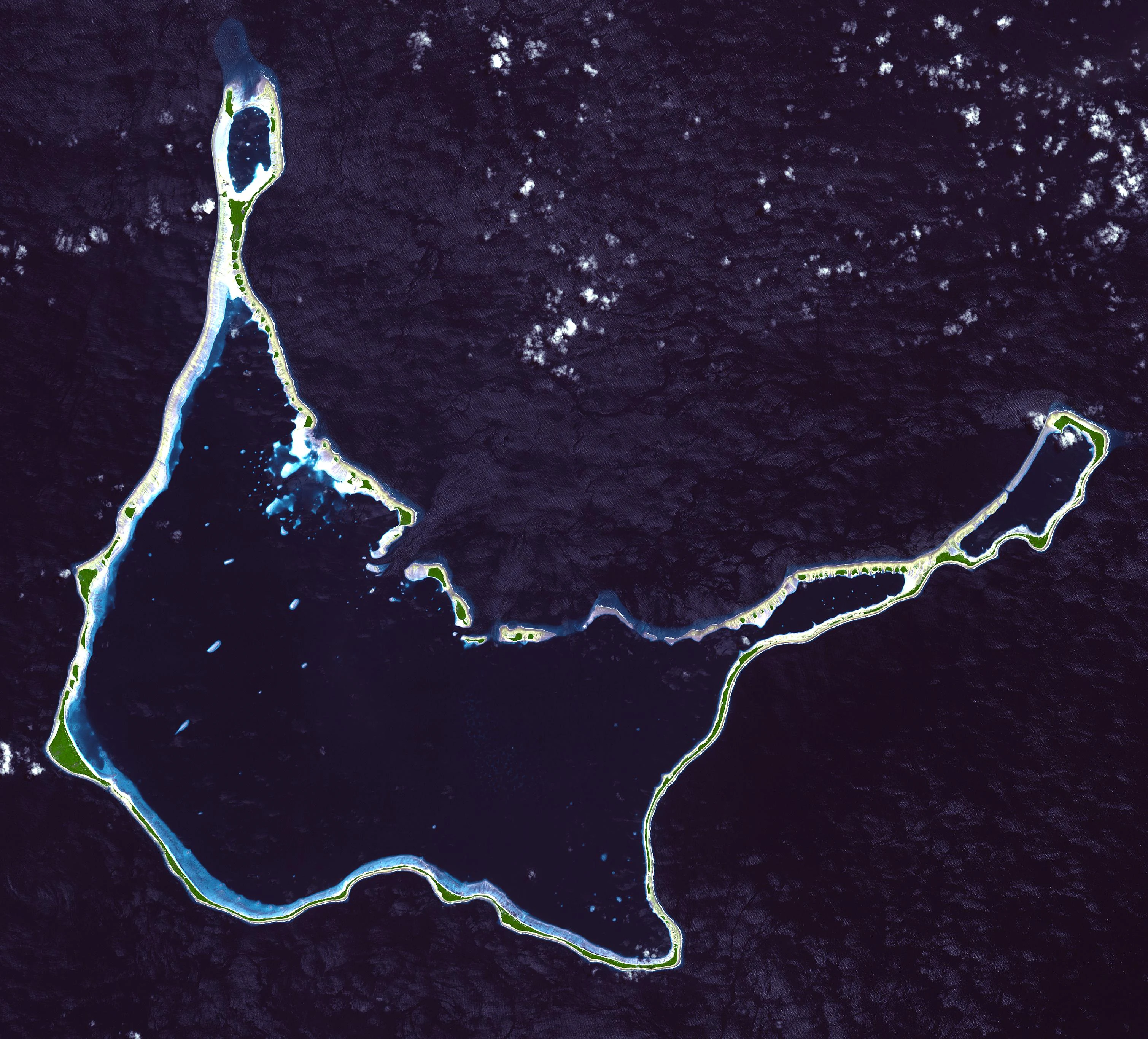 Top-down satellite view of the Arno Atoll, showing its ring of coral islands and internal lagoons set against the deep blue Pacific Ocean.