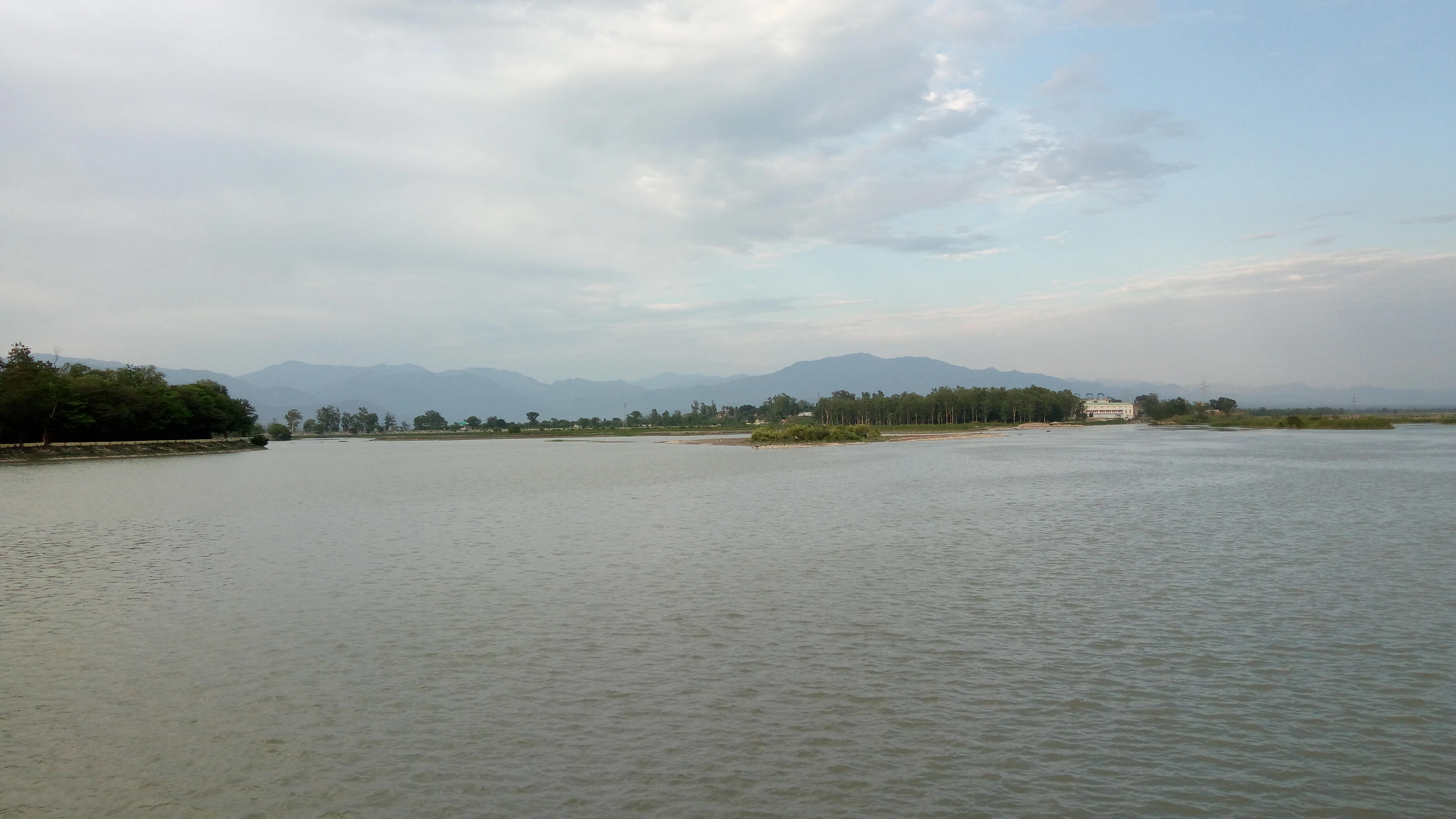 Plano general del embalse de la presa de Asan con una orilla lejana, colinas bajas y un cielo nublado.
