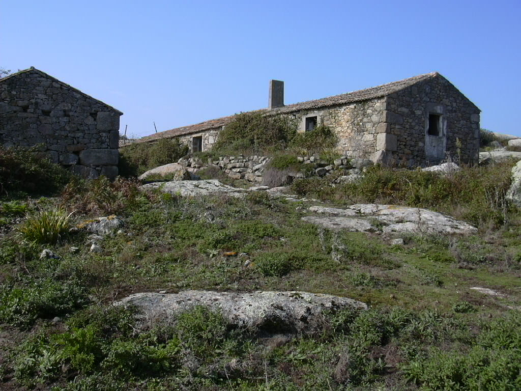 Stone houses and rocky terrain with green vegetation under clear blue sky