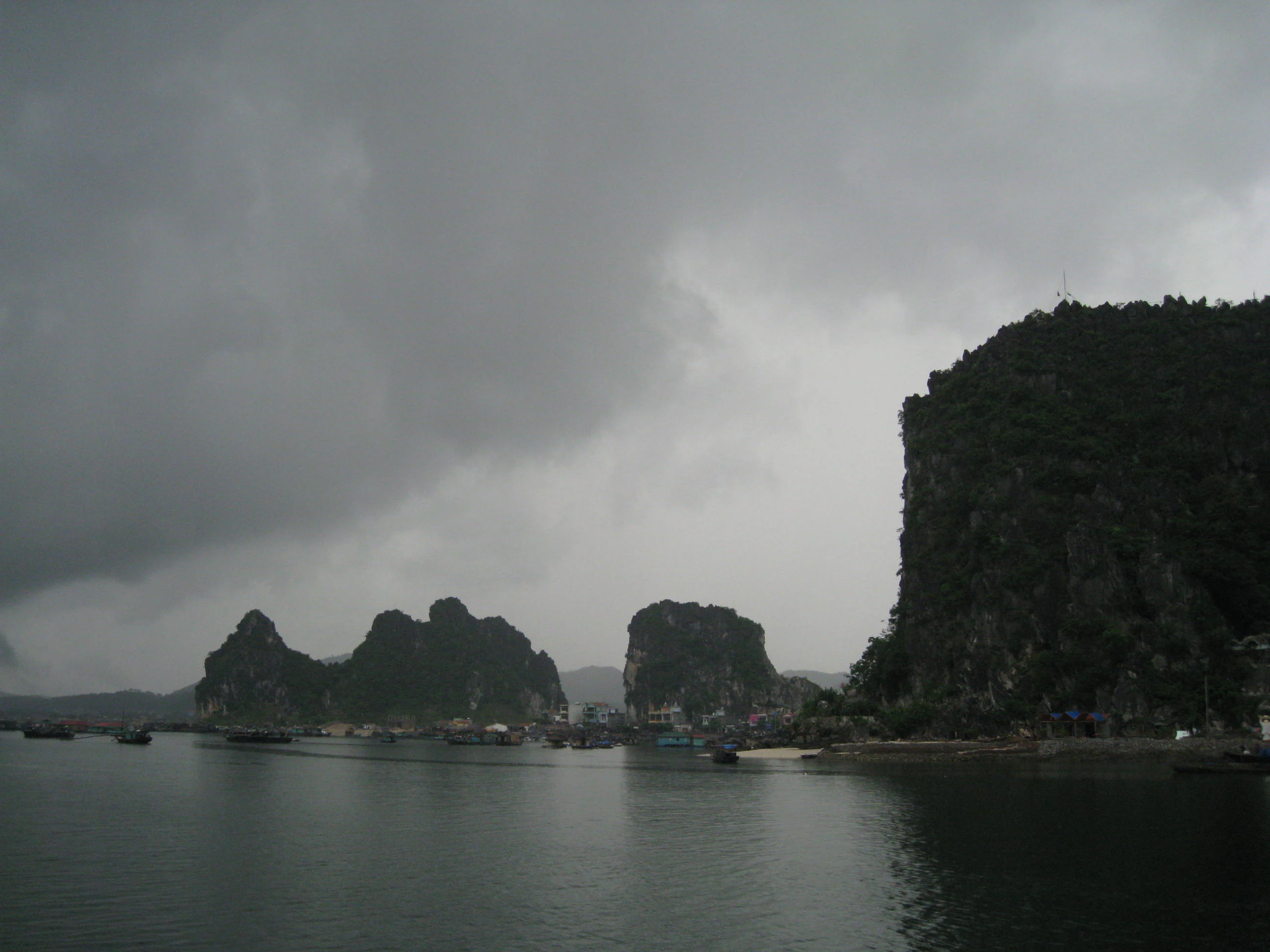 Bái Tử Long Bay with karst islands, calm water, and overcast sky