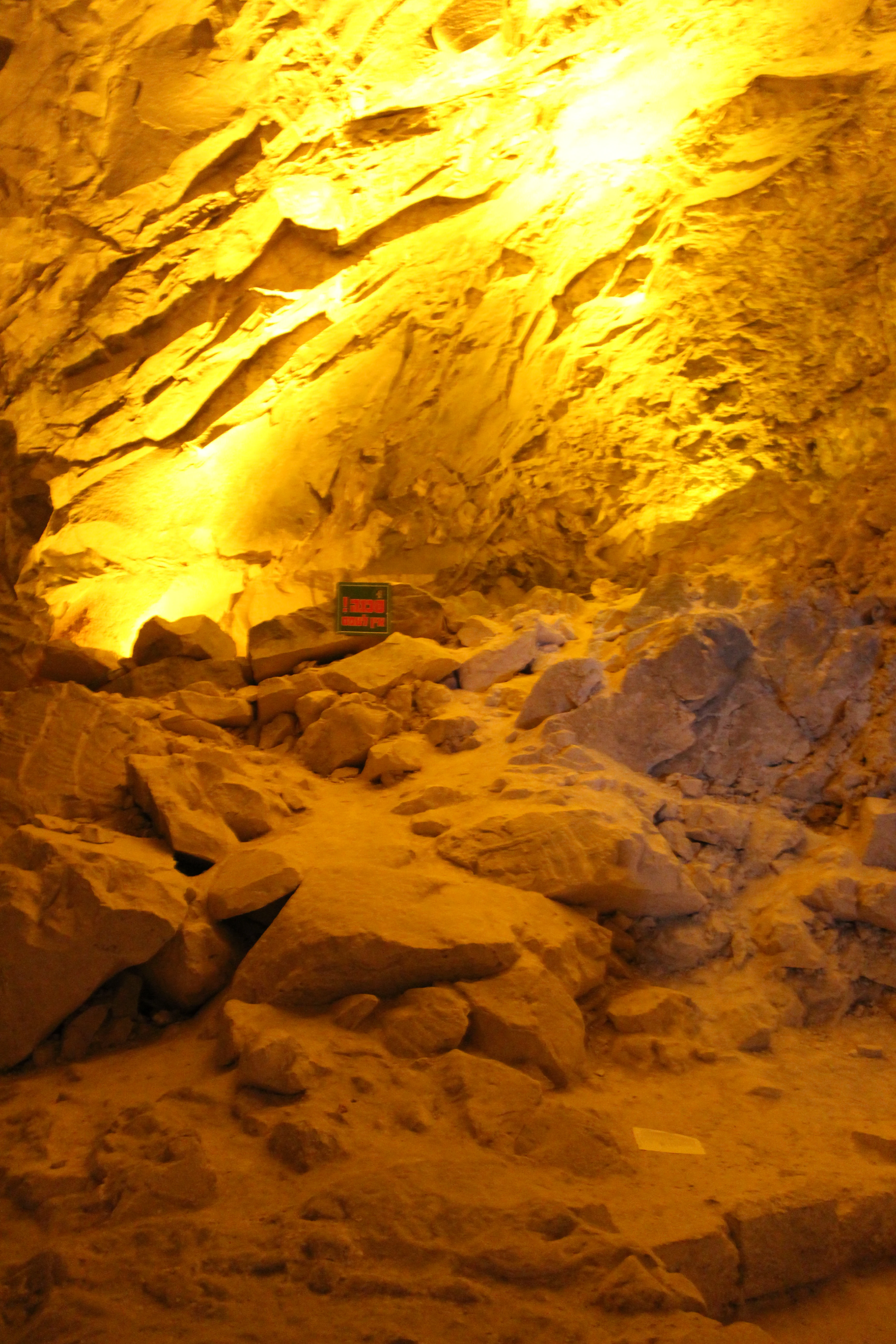 Interior of Catacomb no. 20 with fallen limestone blocks and warm lighting, showing stone walls and a small informational sign