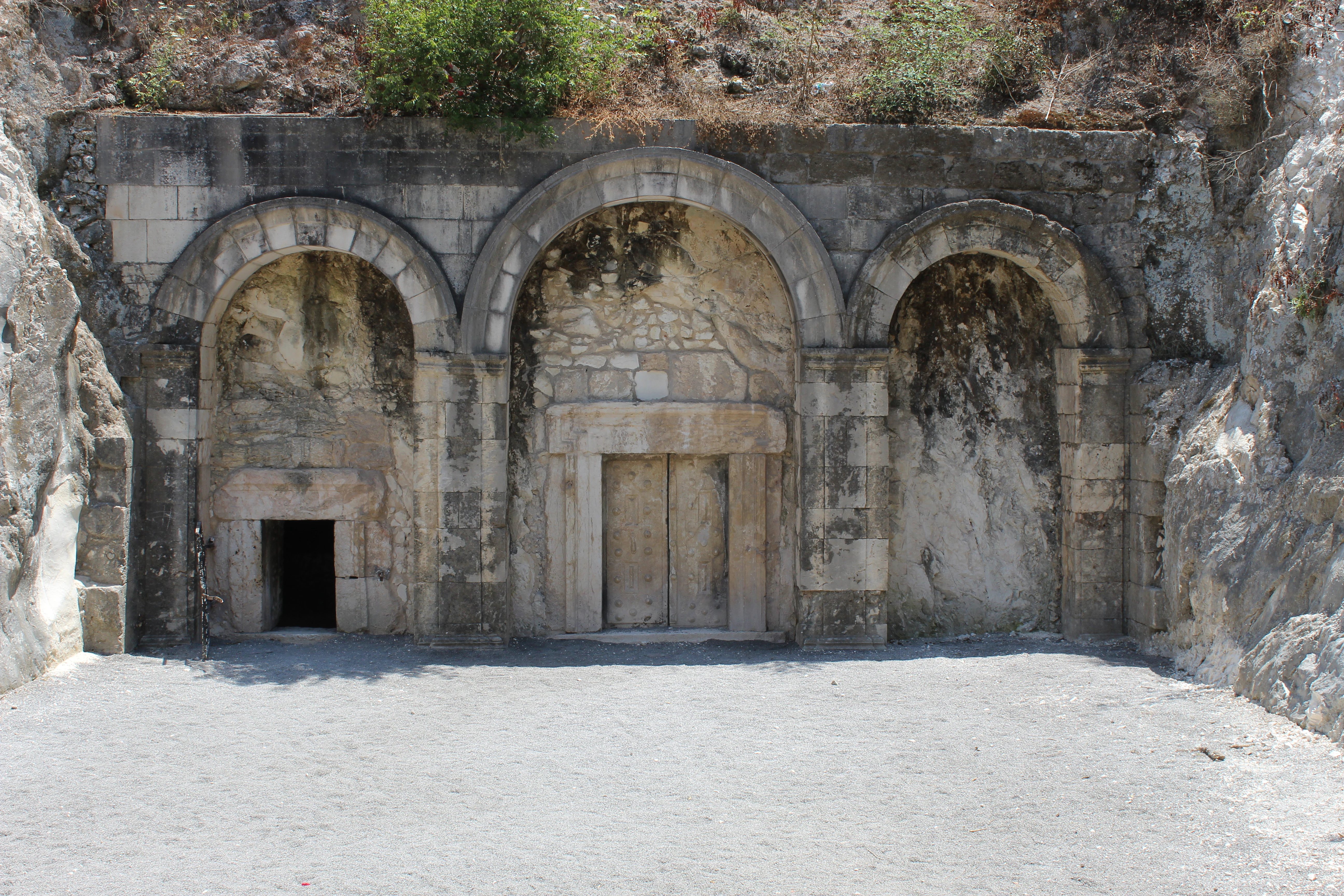 Stone arches and central doorway of Catacomb no. 14 entrance with rocky hillside in background