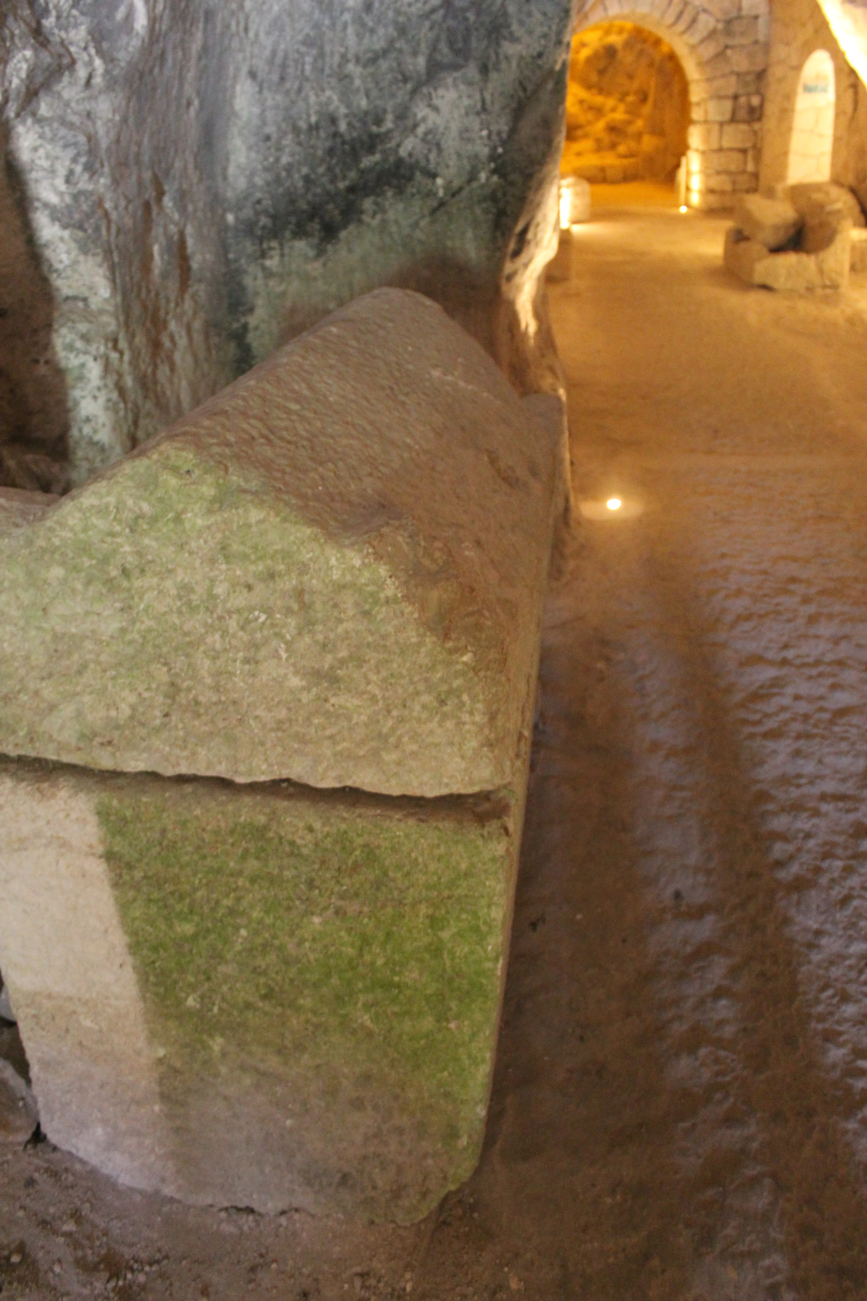 Stone sarcophagus inside an ancient burial chamber with stone walls and a narrow passage