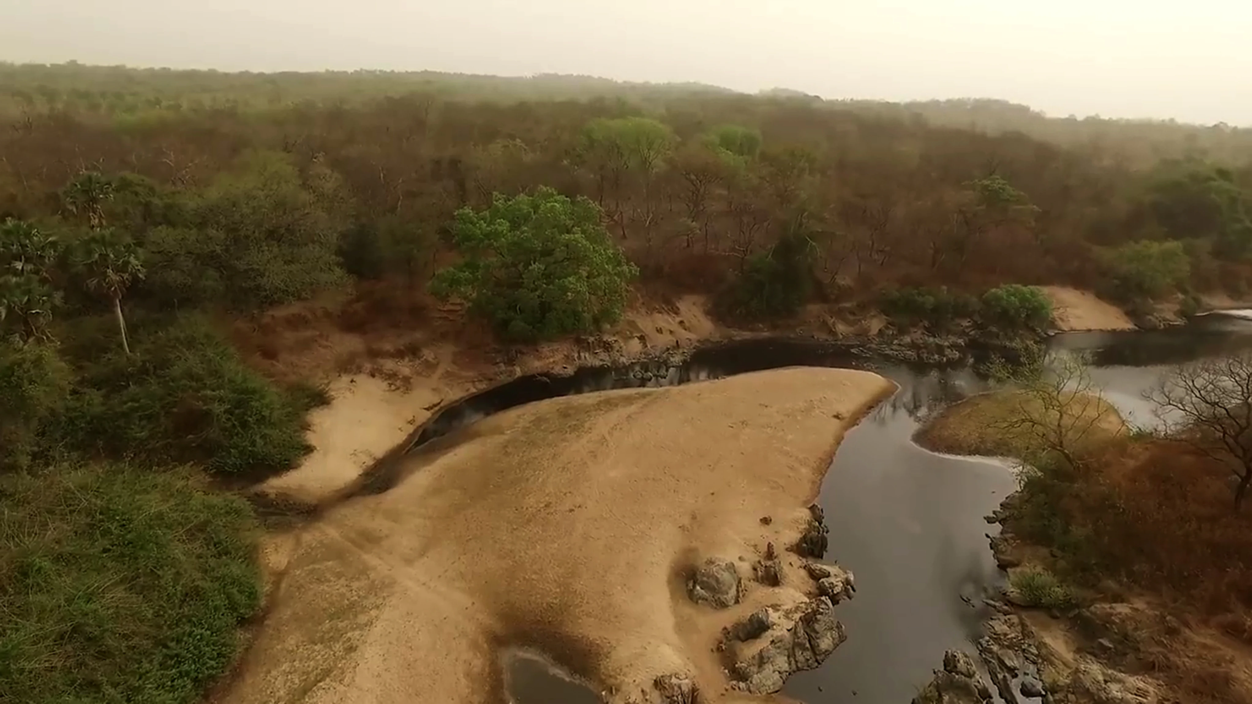 Vista aérea de un recodo de río con orillas arenosas rodeado de zonas boscosas y vegetación