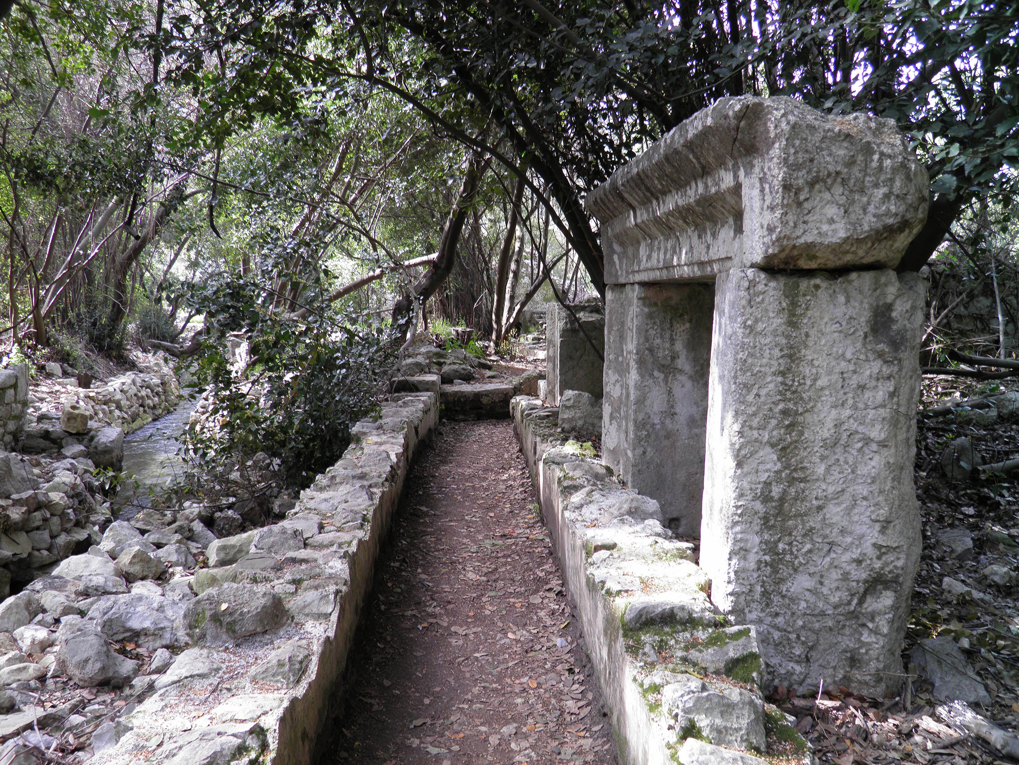 Stone archway structure with a dirt path surrounded by trees and rocks
