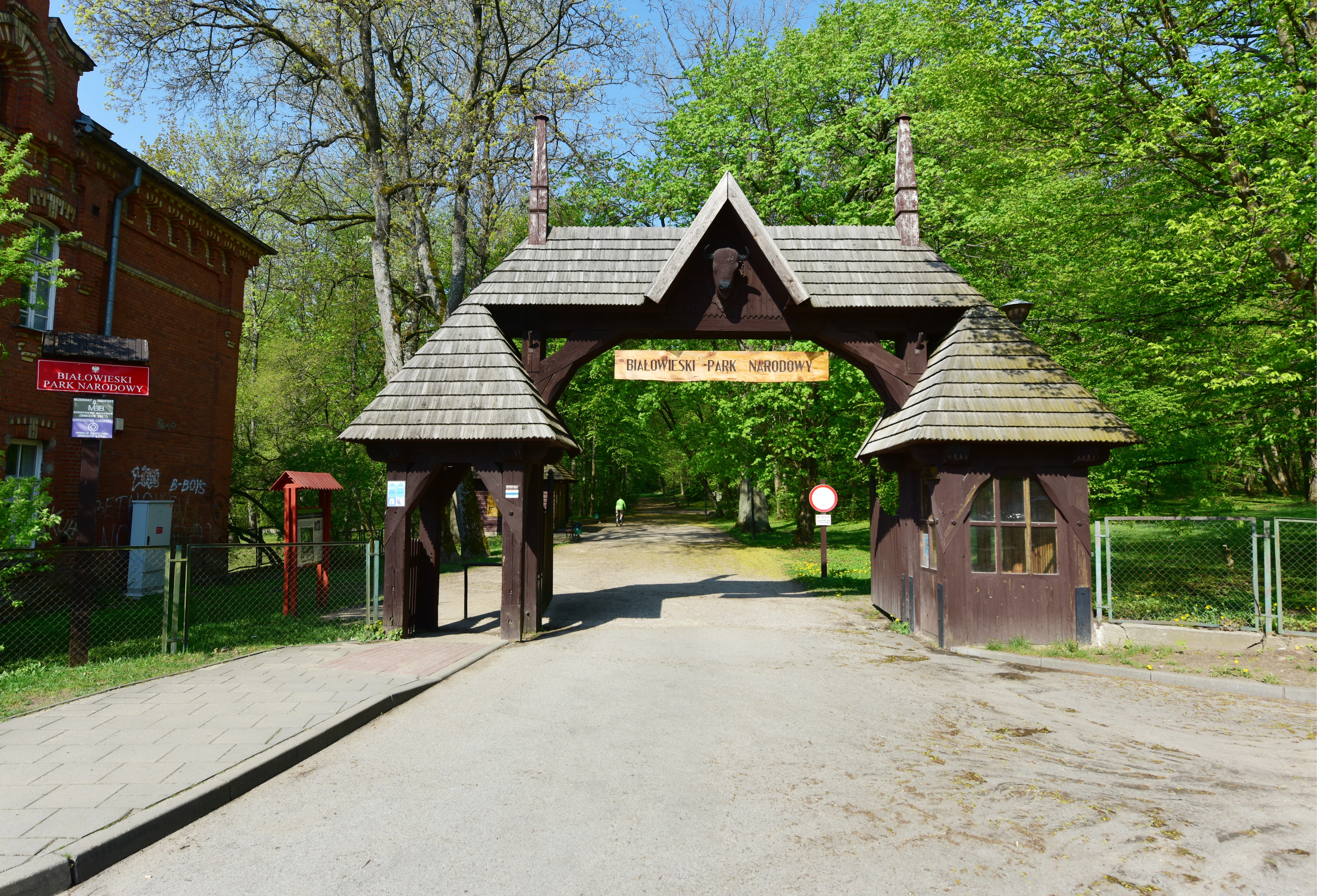 Wooden entrance gate structure at the entrance to a national park with trees and buildings visible in the background