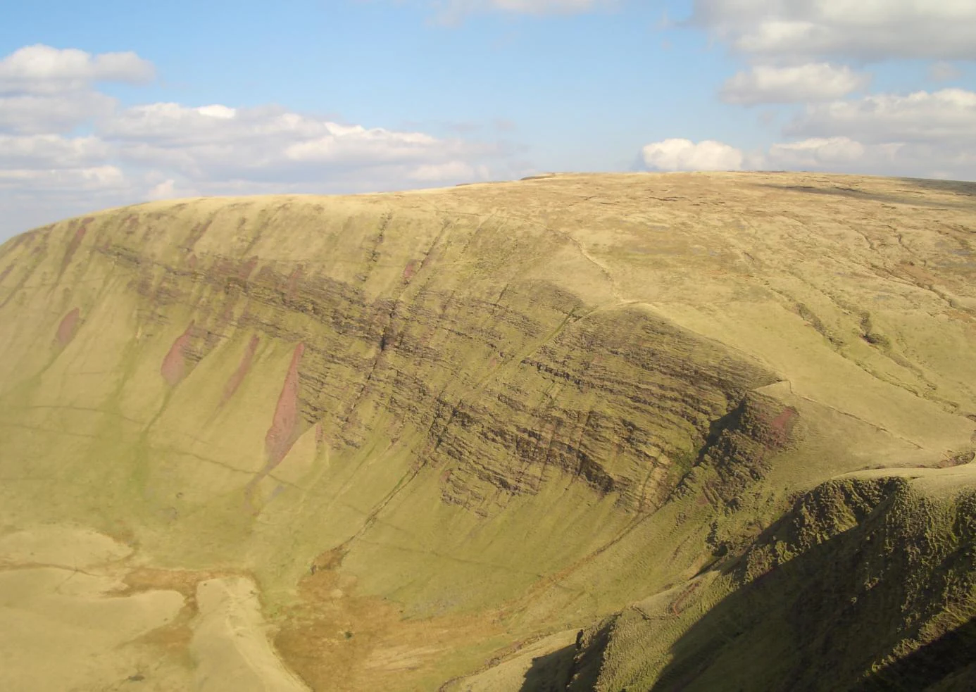 Large mountain with layered rock formations under a partly cloudy sky