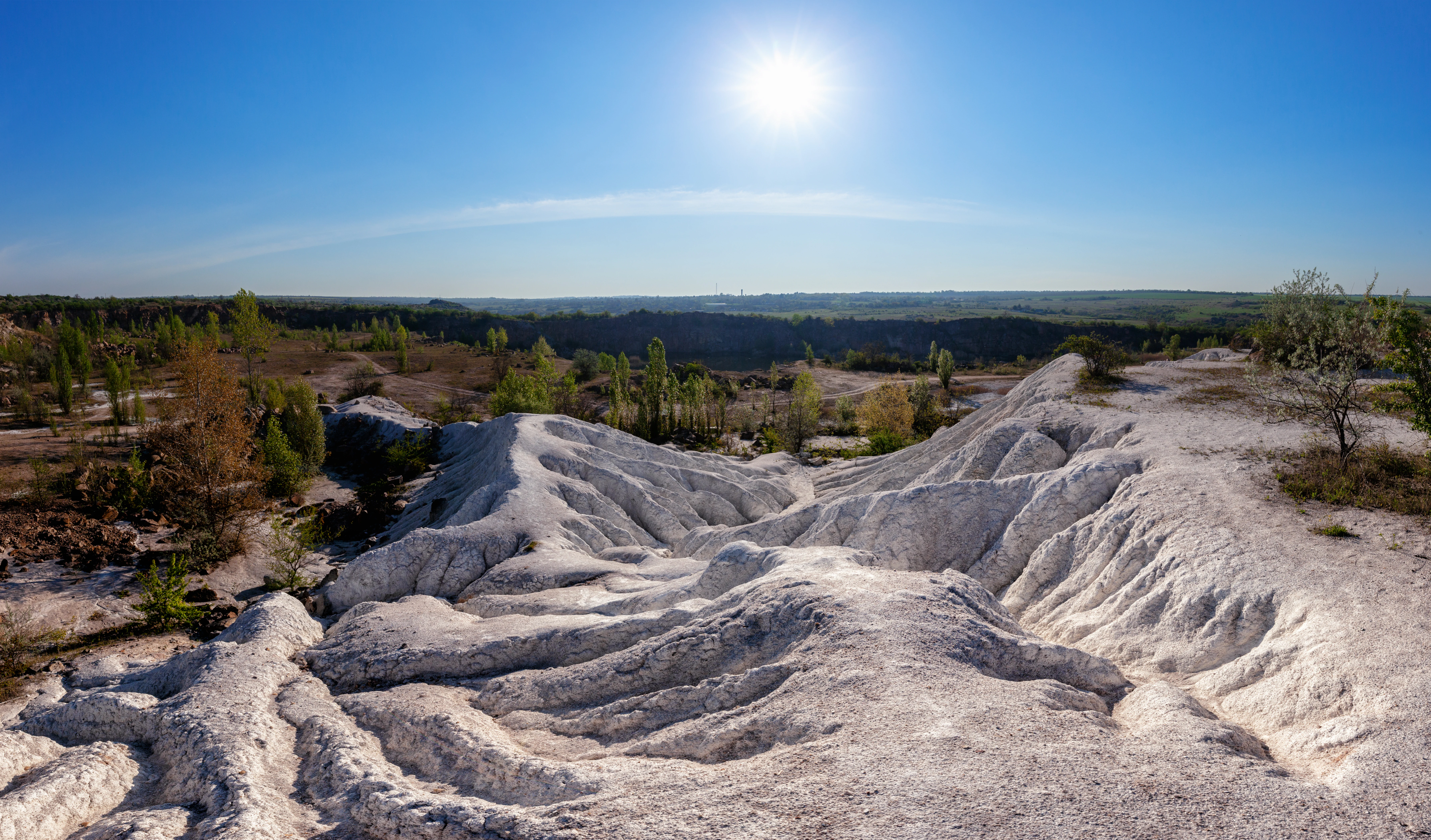 White rock formations in a canyon landscape under a clear blue sky with the sun visible