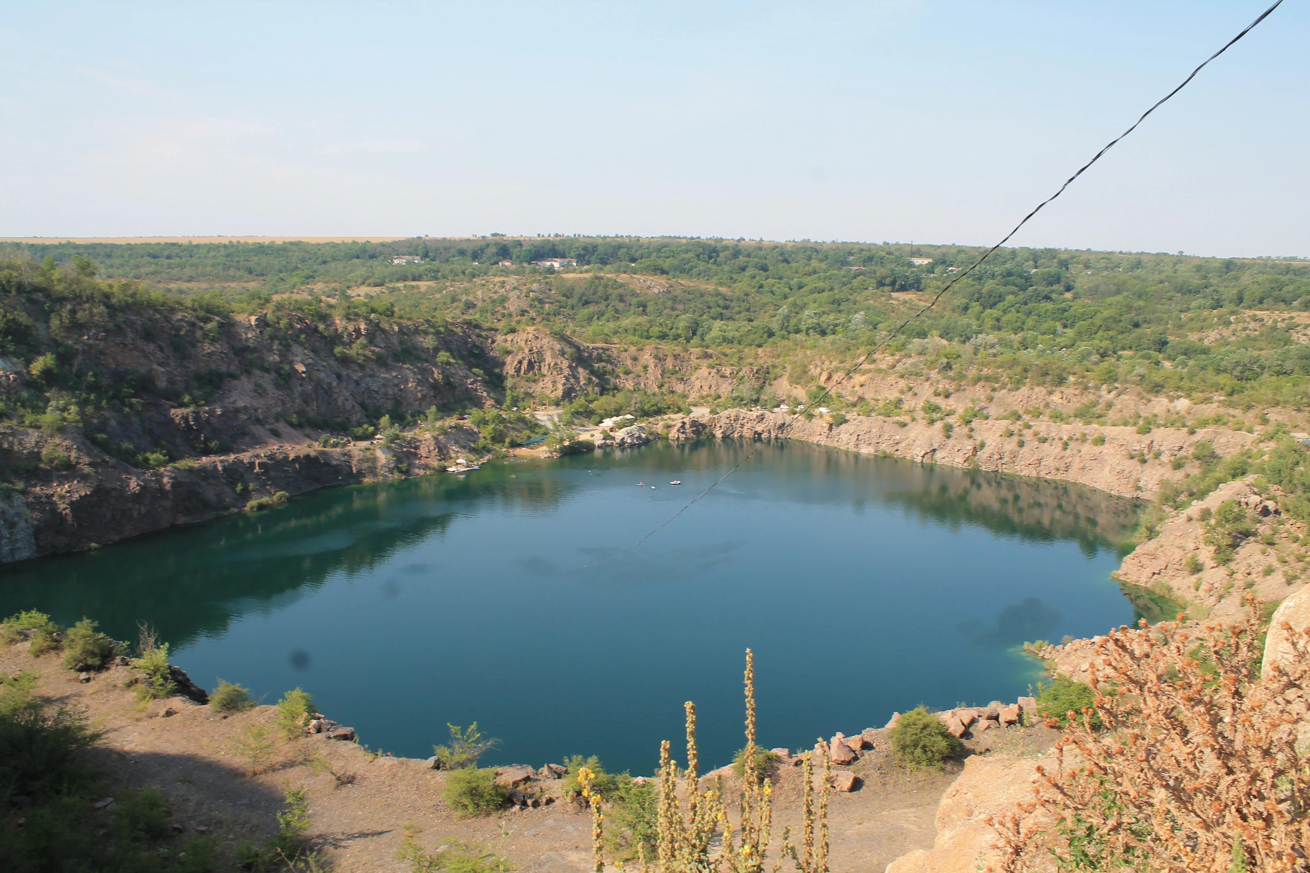 Large blue lake surrounded by rocky cliffs and sparse vegetation under a clear sky