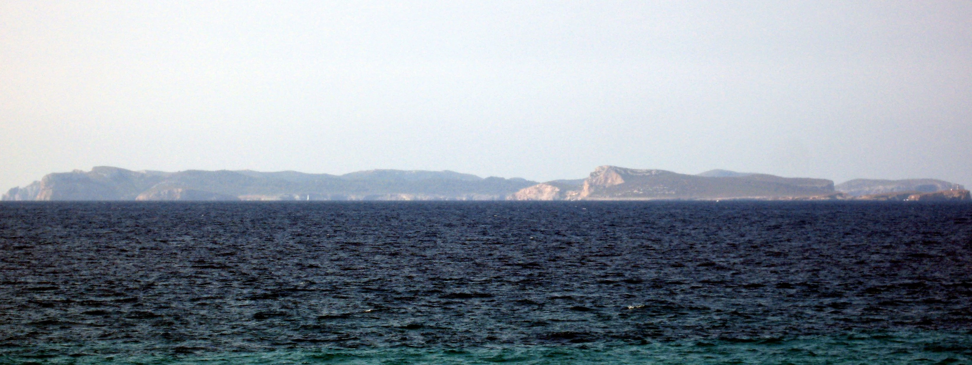 Wide view of the sea with distant landmasses under a clear sky