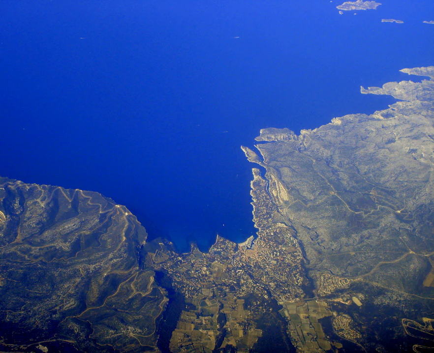 Aerial view showing the coastal area of Cassis Port and Cap Canaille with the Mediterranean Sea, mountains, and surrounding landscape