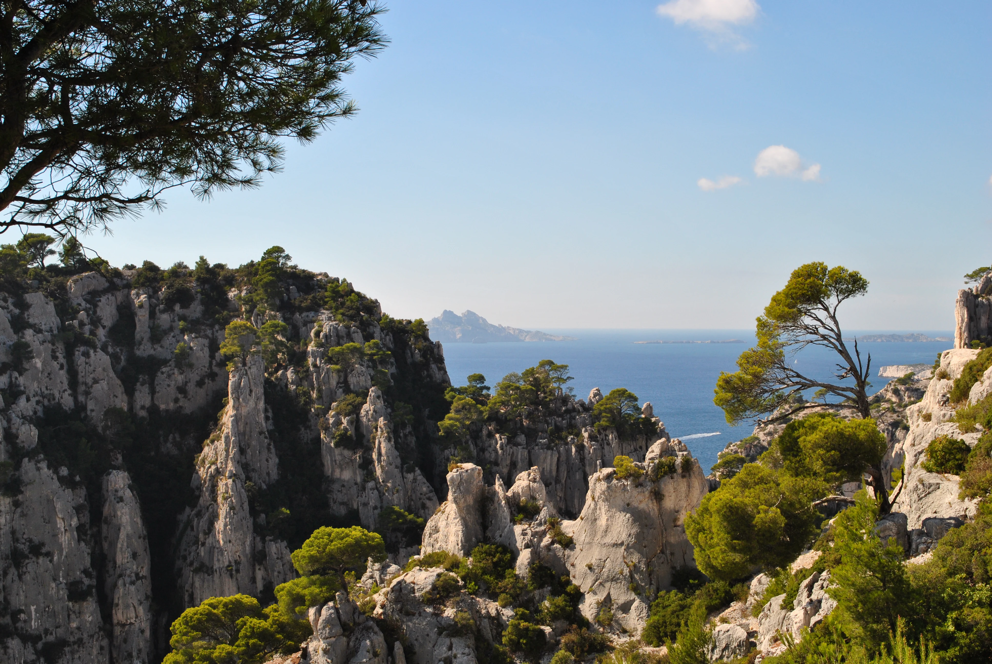 Limestone cliffs and rock formations with Mediterranean Sea in background under clear blue sky.