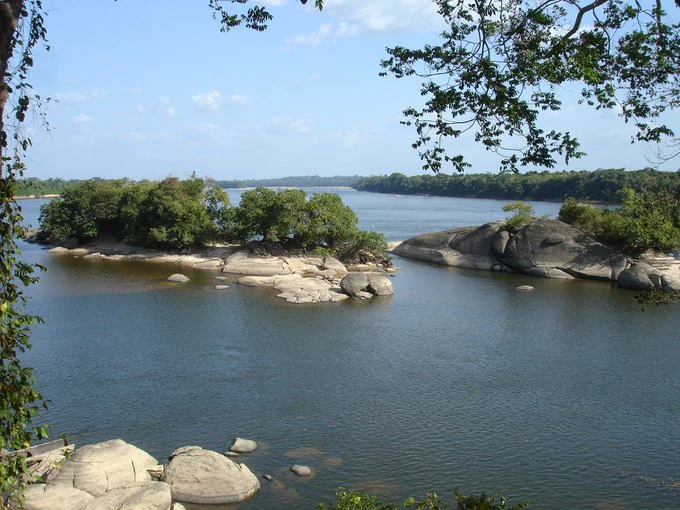 River flowing through Caura National Park with rocky islands, forested shoreline, and clear blue sky