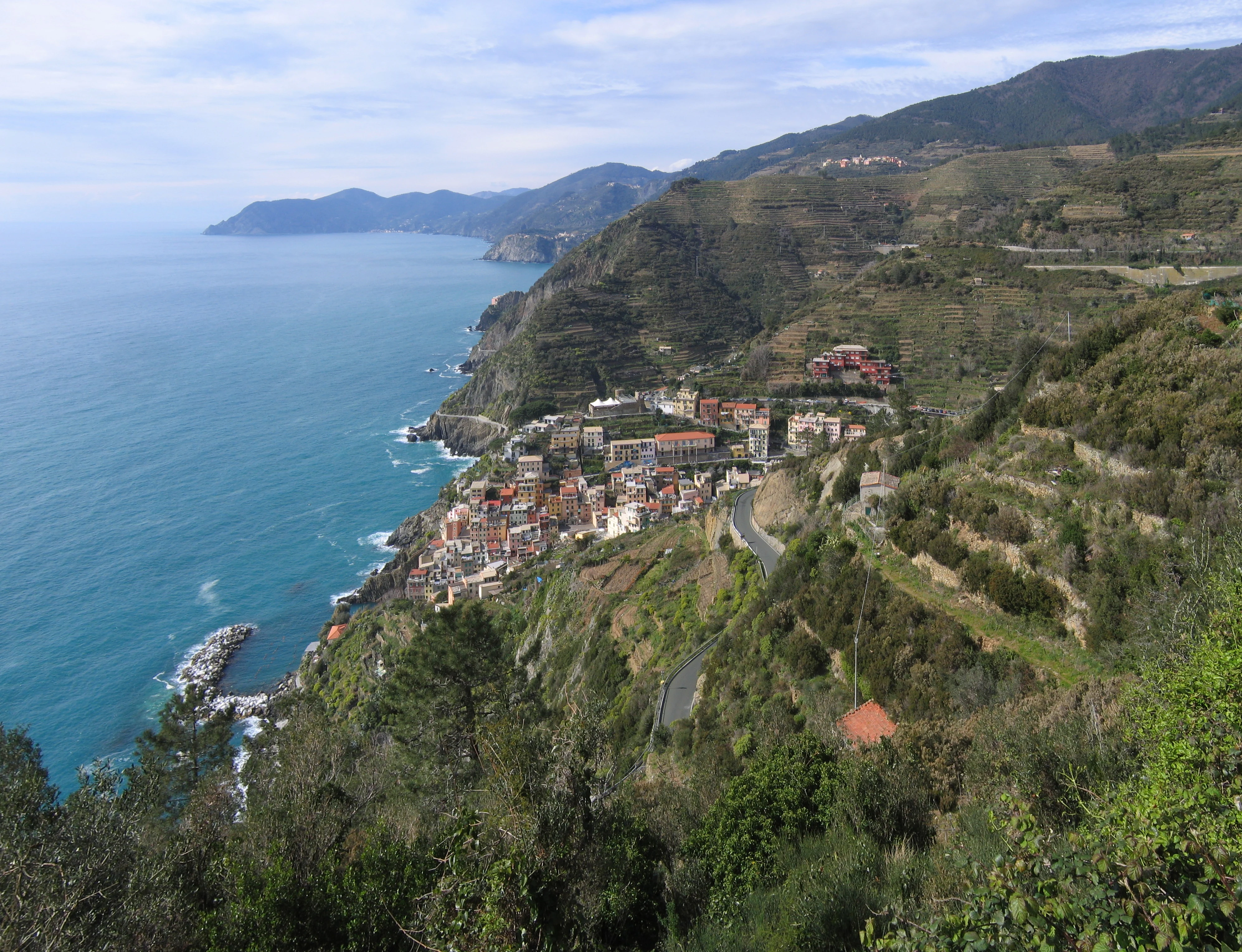 Coastal village with terraced hillsides and blue sea visible from elevated viewpoint