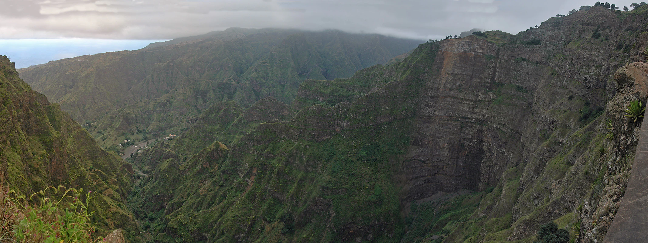 Panoramic view of a large caldera with steep rocky cliffs and lush green vegetation in the valley