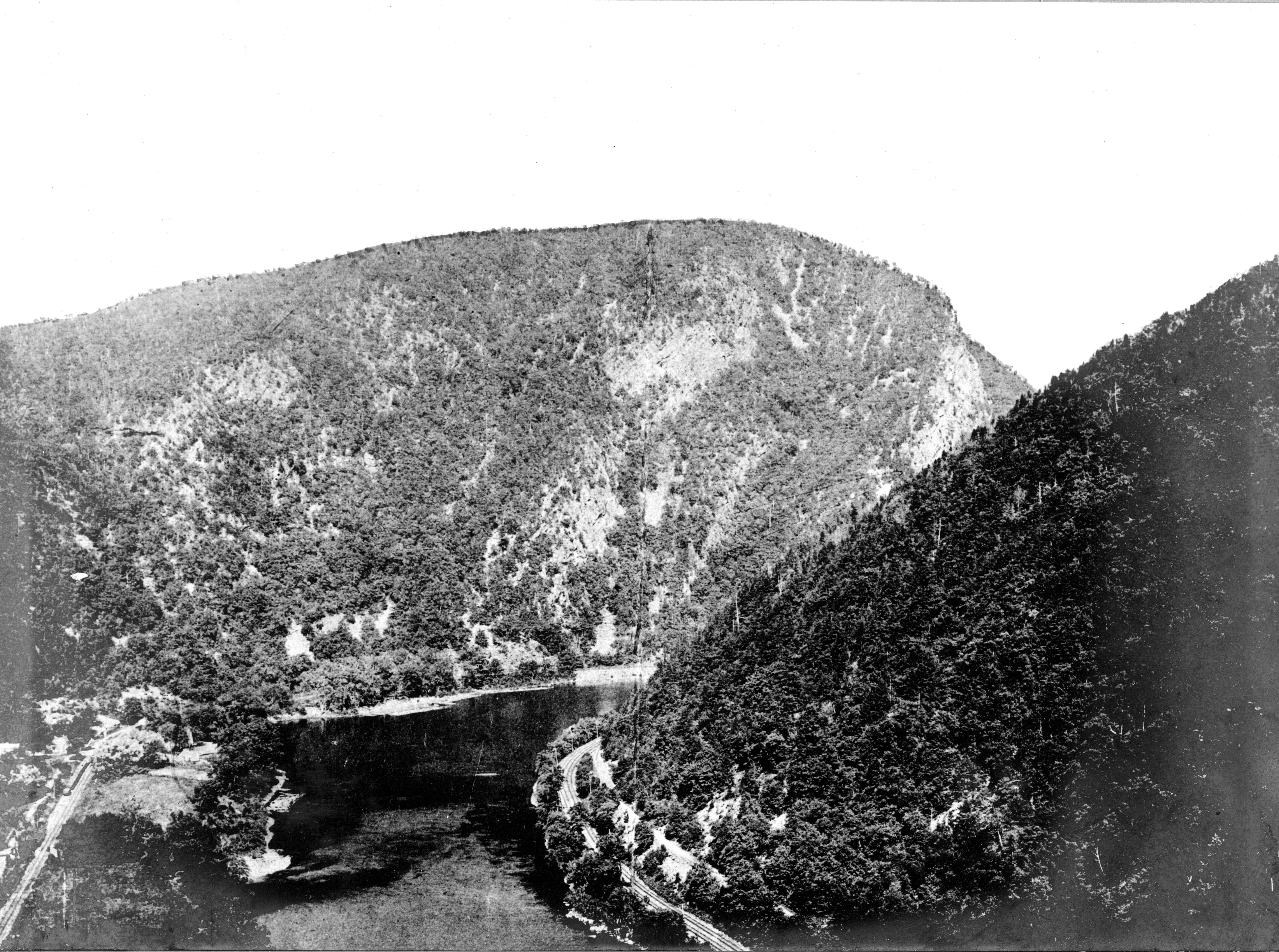 A black and white archival photograph of the Delaware Water Gap, featuring a river flowing through a steep mountain pass.