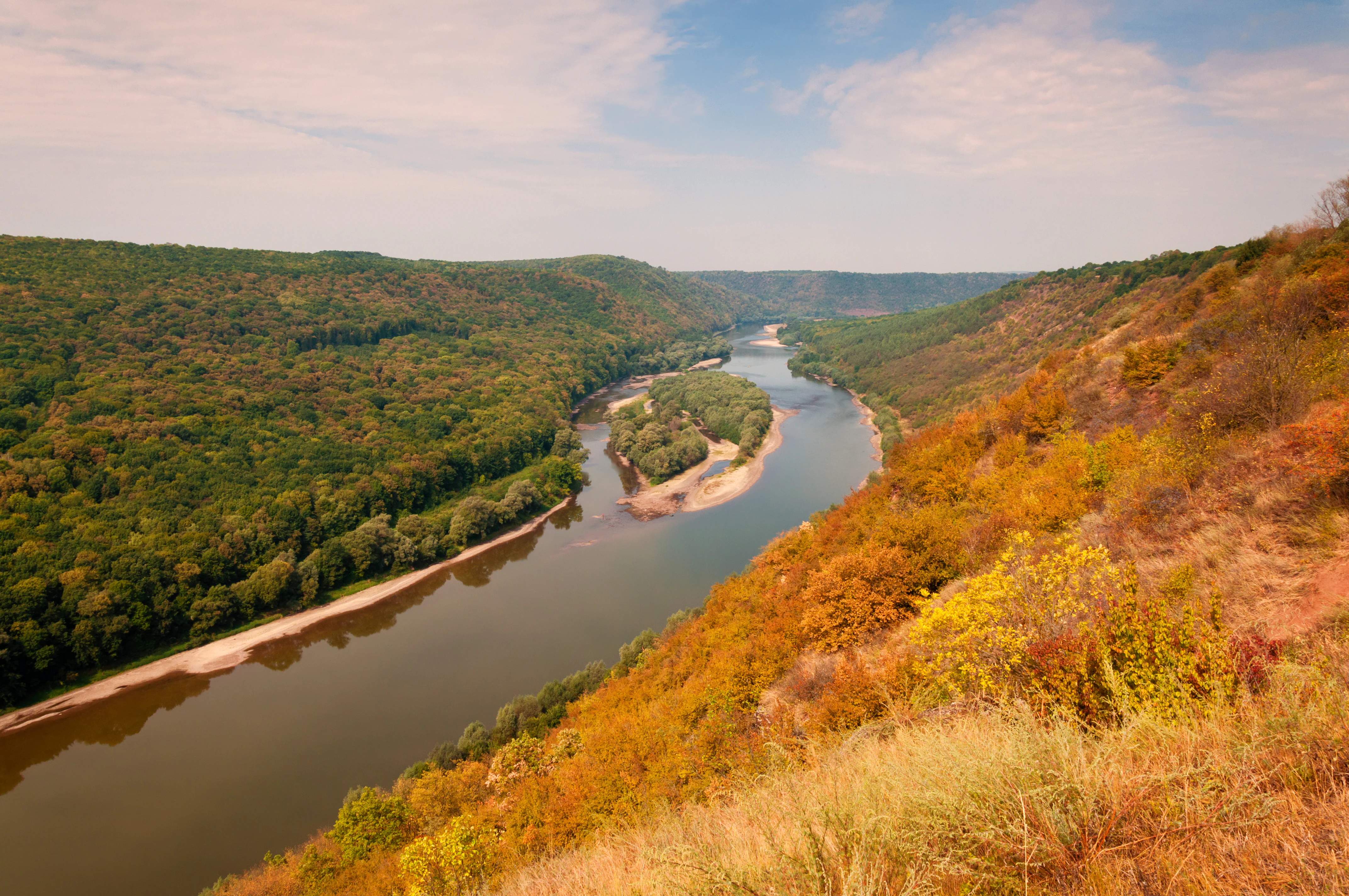 Wide landscape view of the Dniester River winding through forested hills with autumn foliage