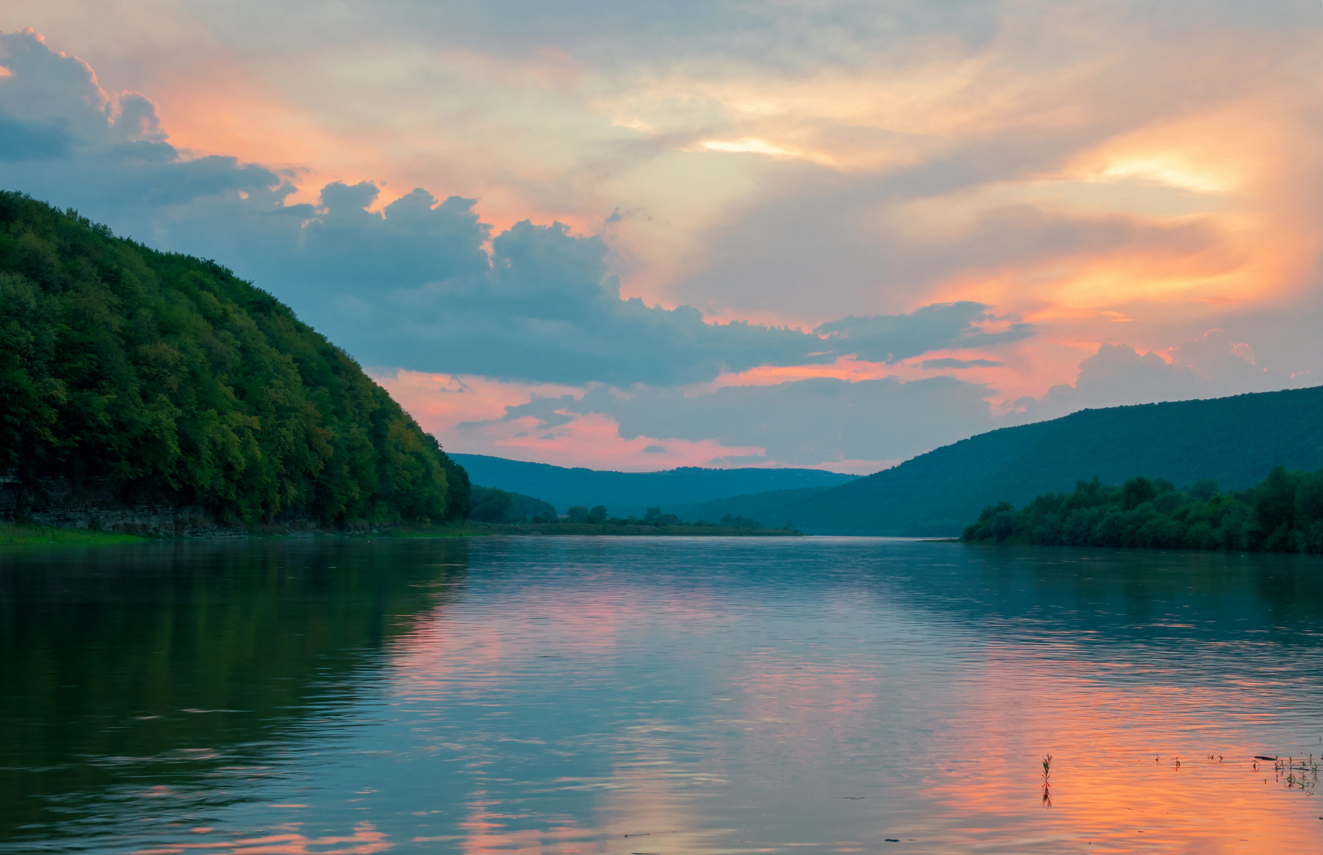 River reflecting sunset sky with forested hills on both sides