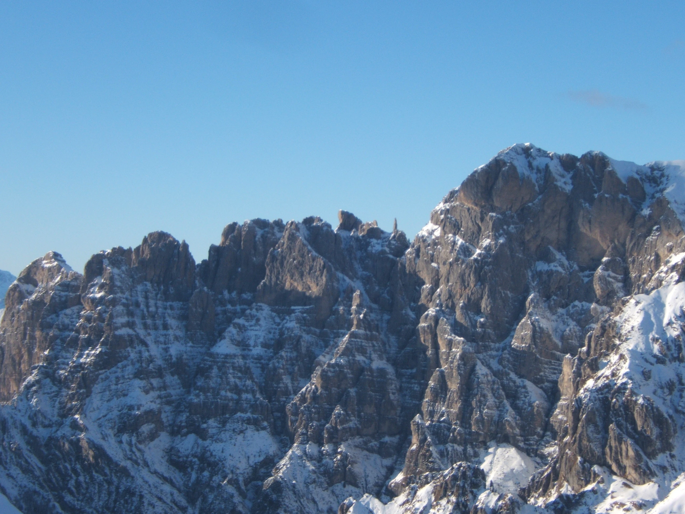Snow-covered mountain peaks with rocky cliffs and clear blue sky