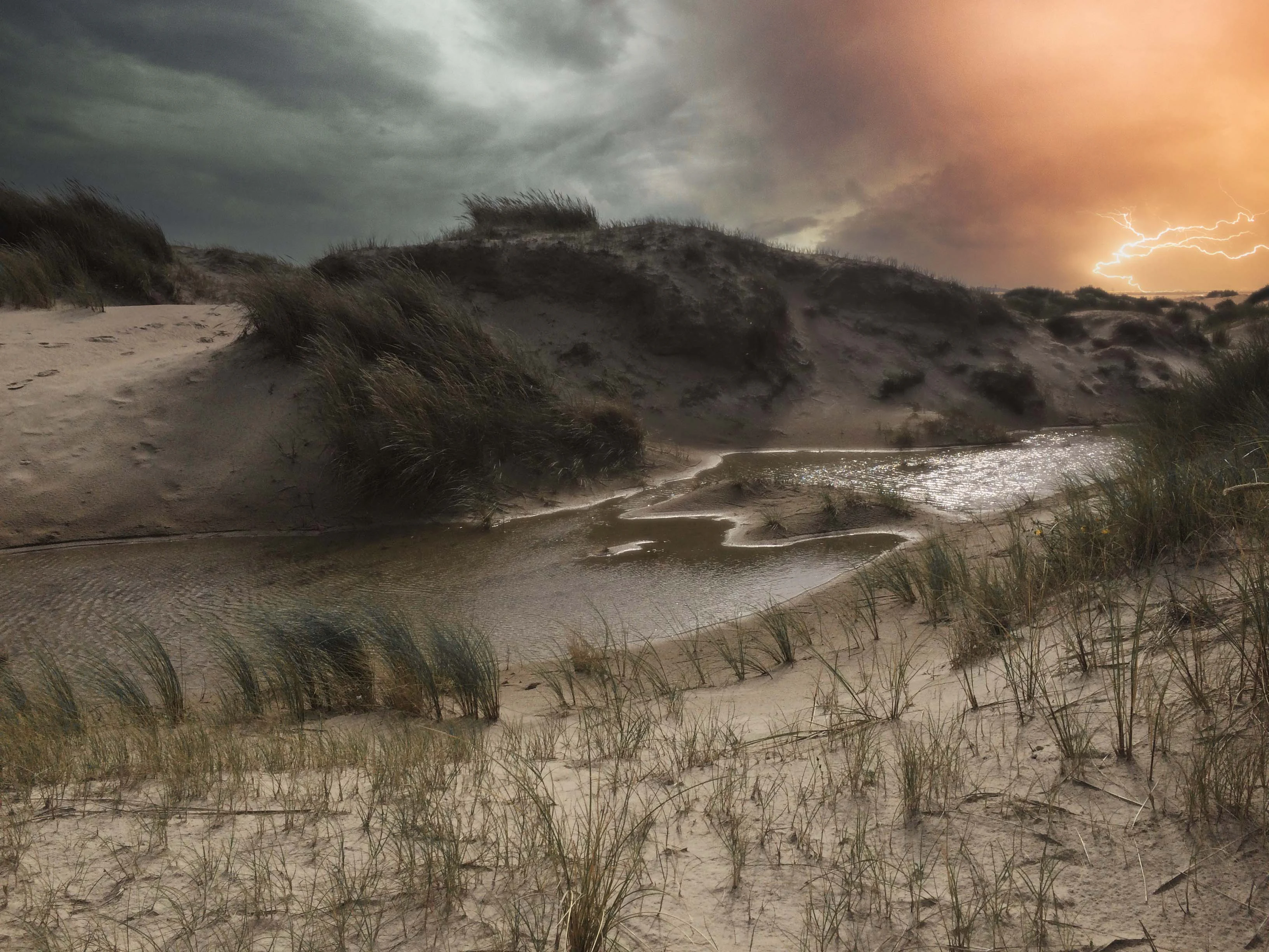 Sandy dune landscape with sparse vegetation, water channels, and stormy sky with dark clouds and lightning