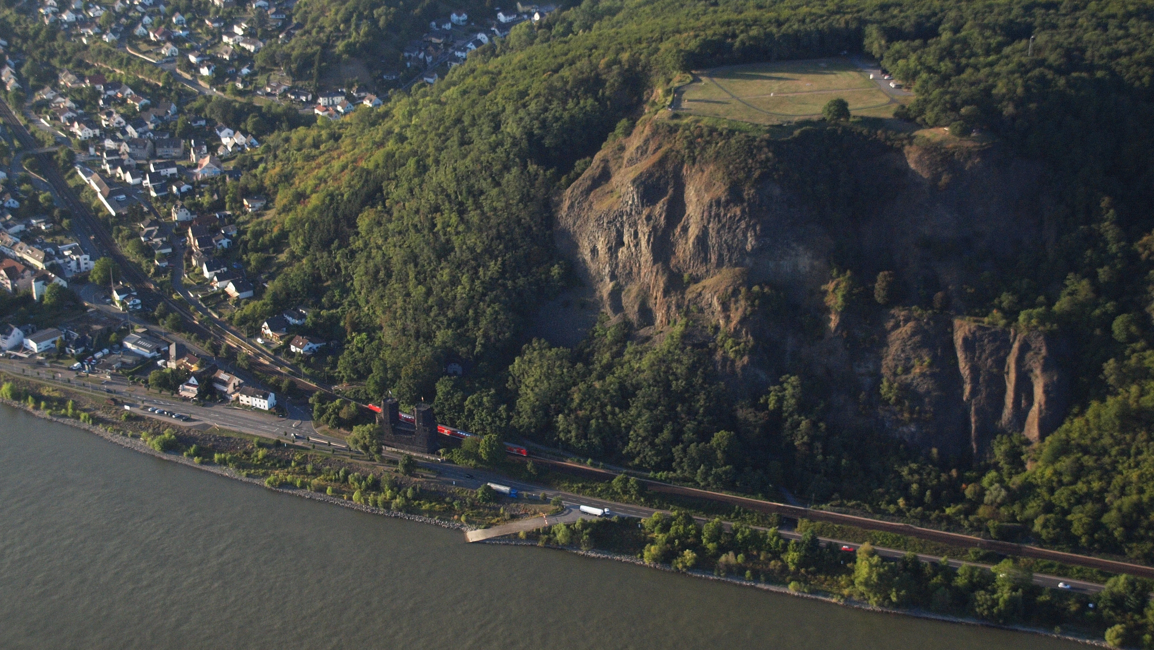 Aerial view of Erpeler Ley, a prominent basalt cliff face rising above the Rhine river, with the town of Erpel visible at the base.
