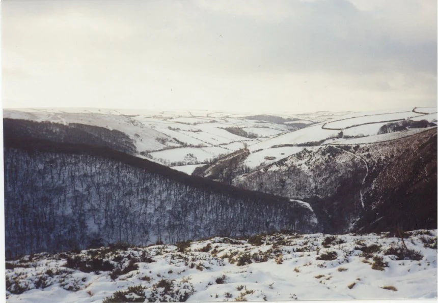 Snow-covered hills and valleys in Exmoor National Park with patches of exposed vegetation