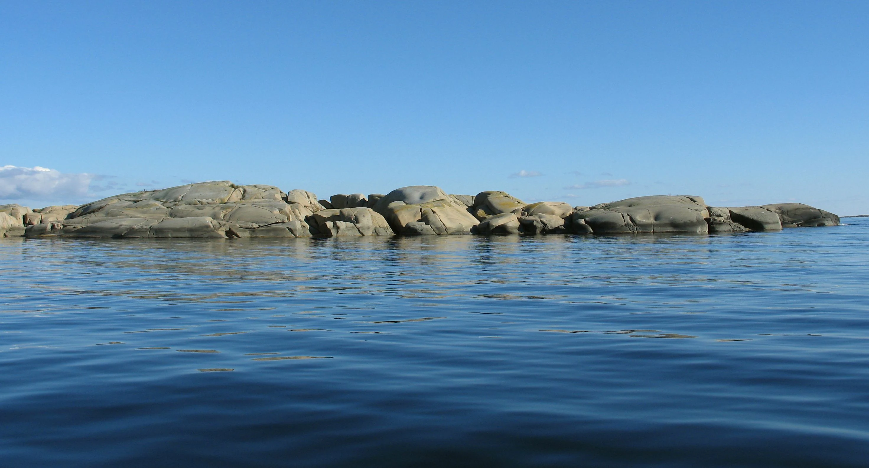 Calm blue water with rocky islets under a clear blue sky