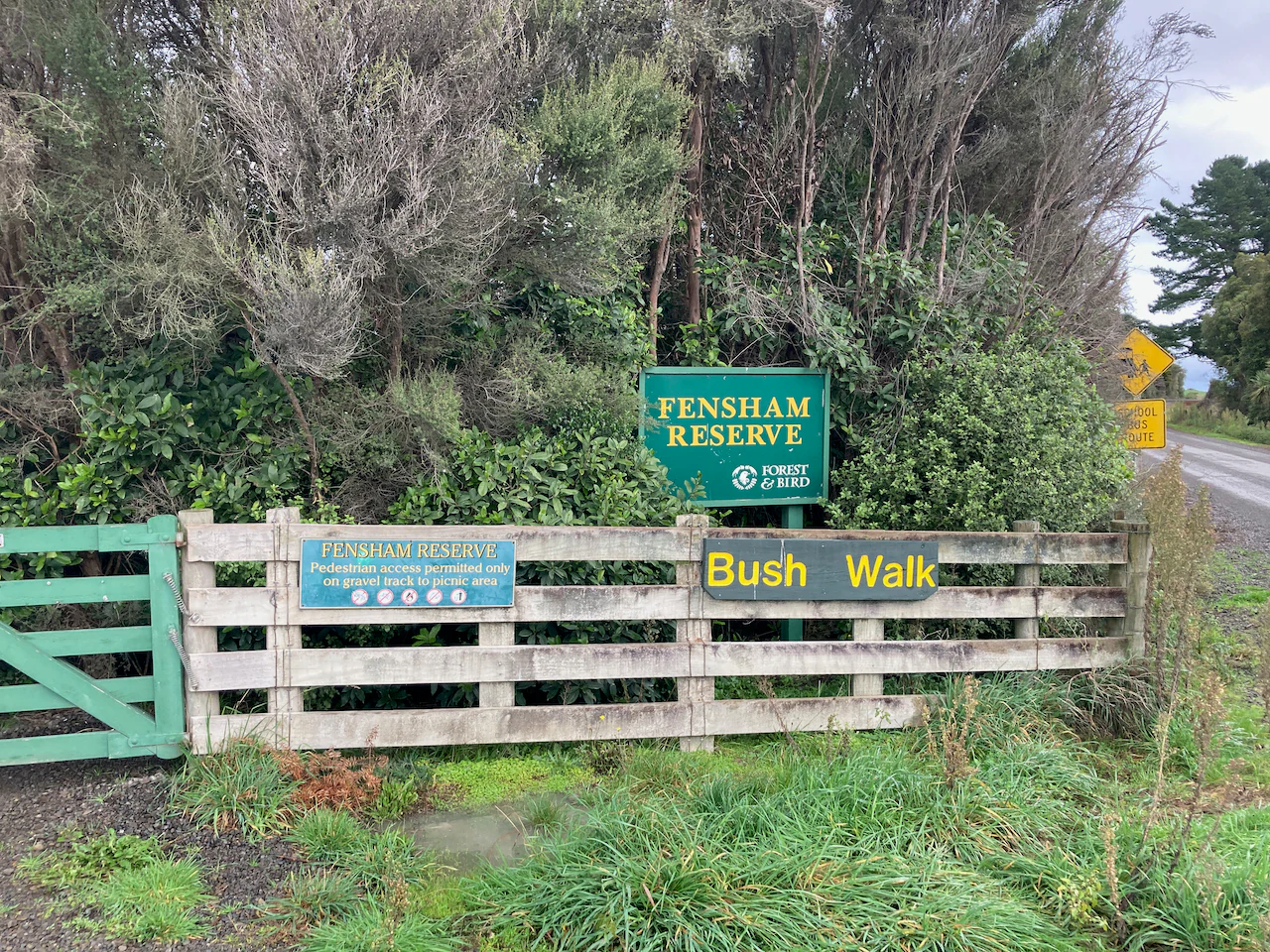 A green and white wooden gate marks the entrance to Fensham Reserve, featuring signage for the park name and bush walk.