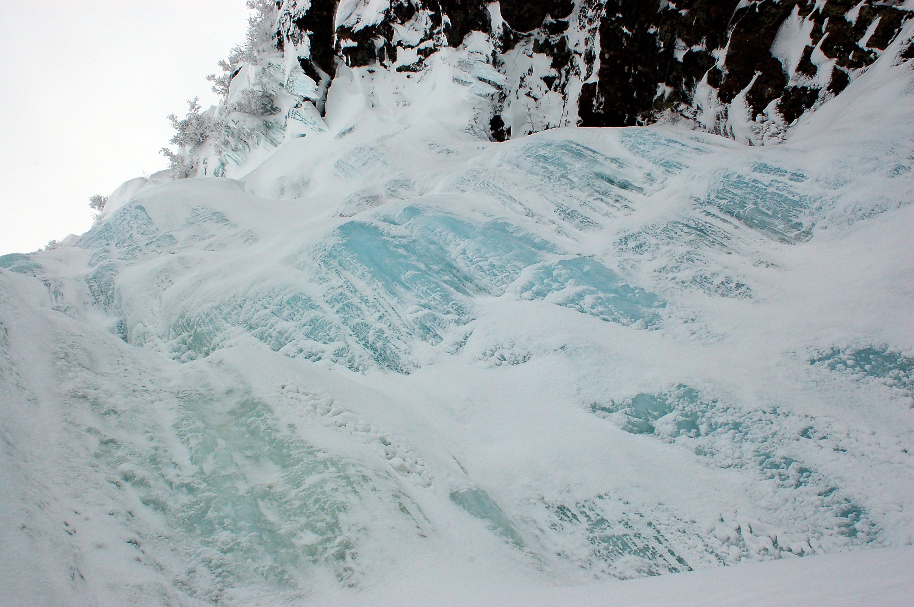 Frozen waterfall with ice formations on rocky cliffs and snow-covered ground