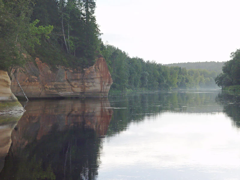 Calm river reflecting sandstone cliffs and forested shoreline