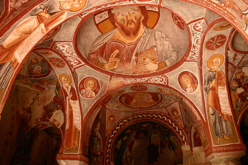 Interior view of a rock chapel with painted religious frescoes on the ceiling and walls