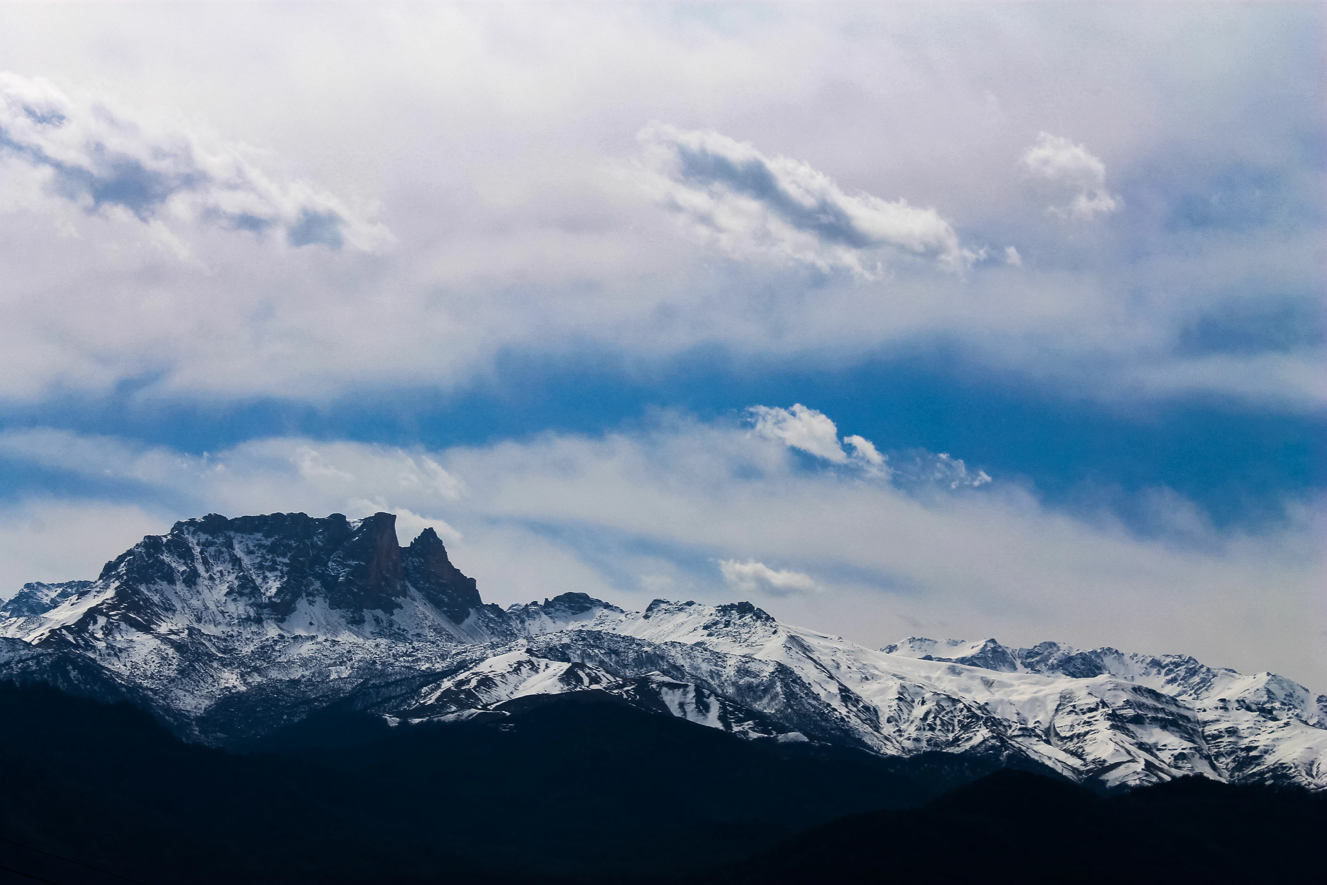 Snow-covered mountain peaks with clouds in the sky