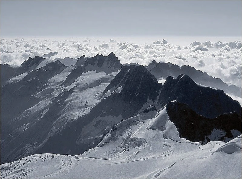 Snow-covered mountain peaks and glaciers under a cloudy sky in Gran Paradiso National Park