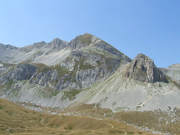 Rocky mountain peaks with grassy slopes and a clear blue sky in Gran Sasso and Monti della Laga National Park.