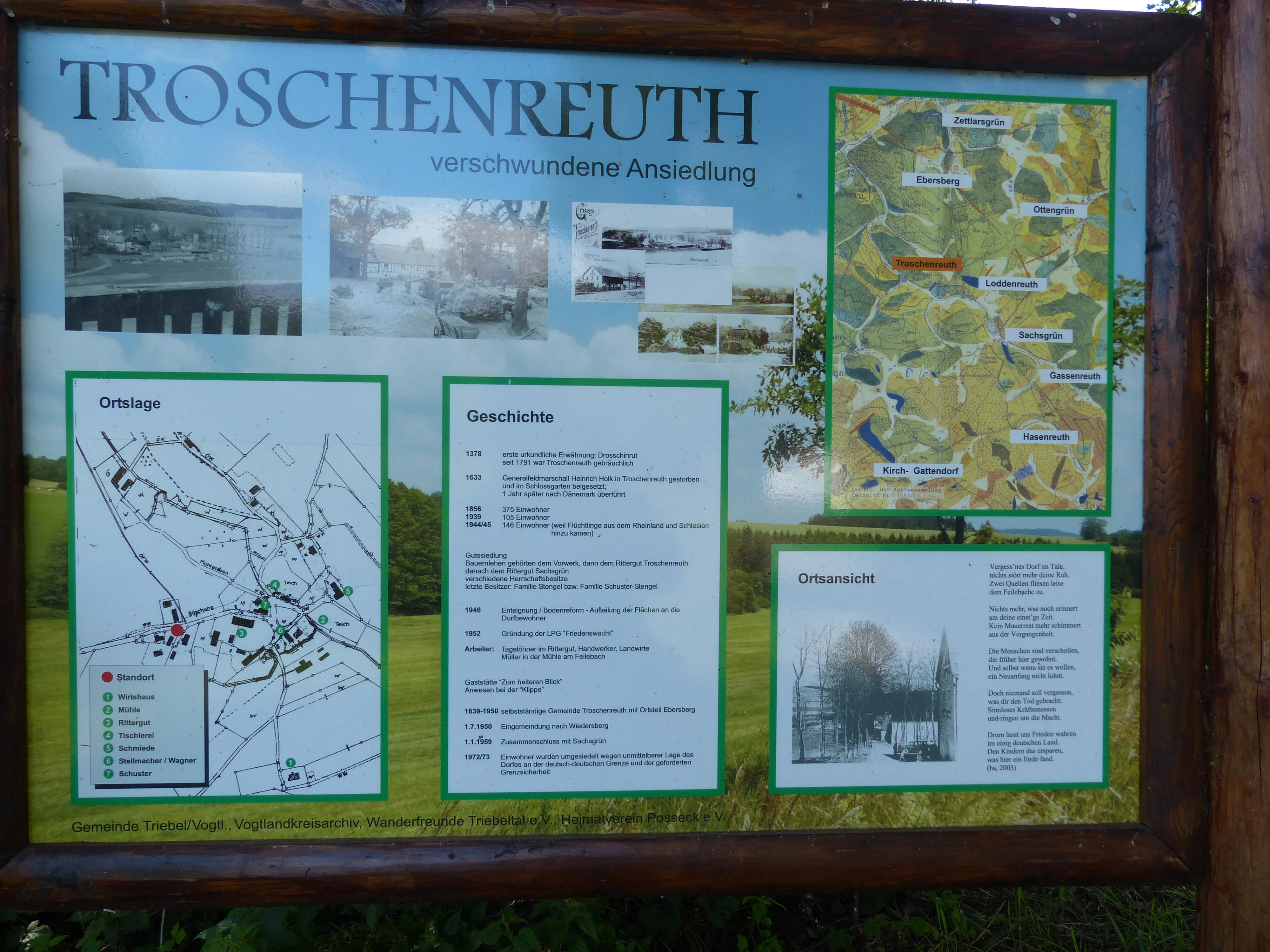An informational outdoor signage board about the deserted settlement Troschenreuth, featuring maps, historical text, and photos of the former village site.