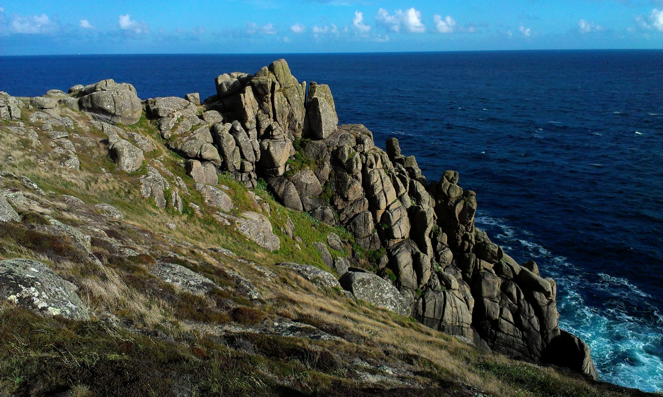 Rugged granite rock cliffs rising above the dark blue ocean at Gwennap Head.