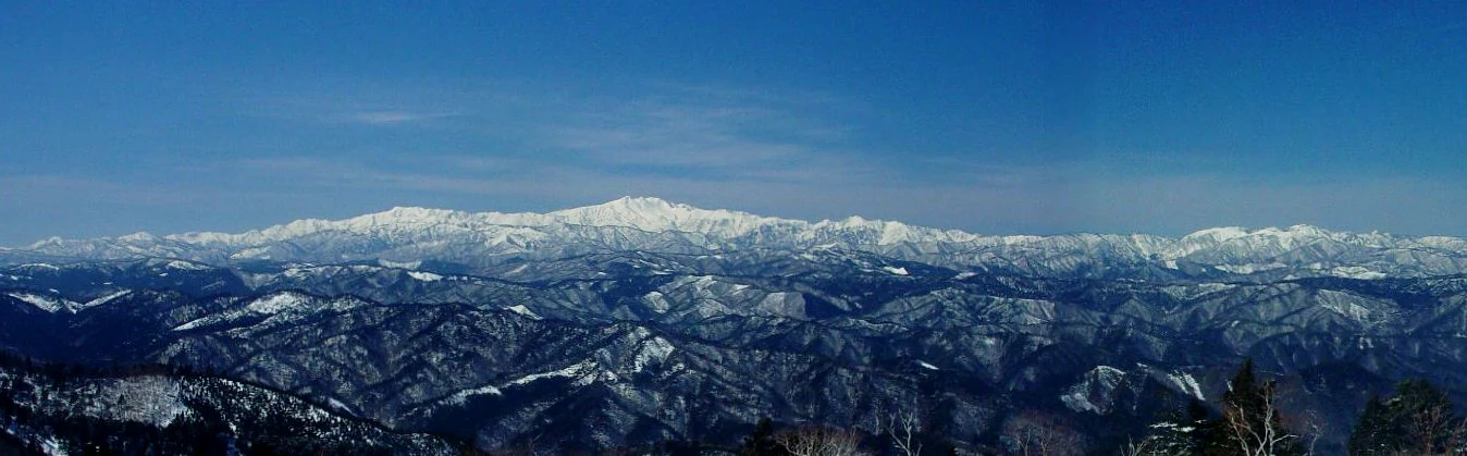 Vista panorámica de picos y crestas montañosas cubiertas de nieve bajo un cielo azul despejado