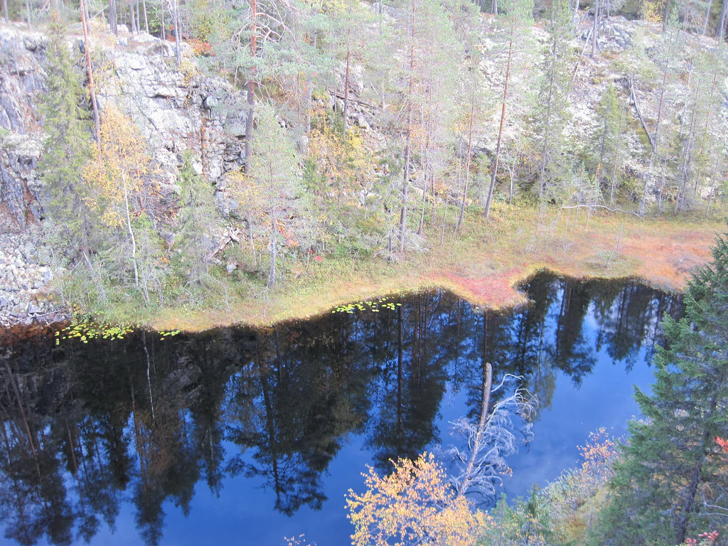 Calm lake reflecting rocky cliffs and forested shoreline with autumn foliage